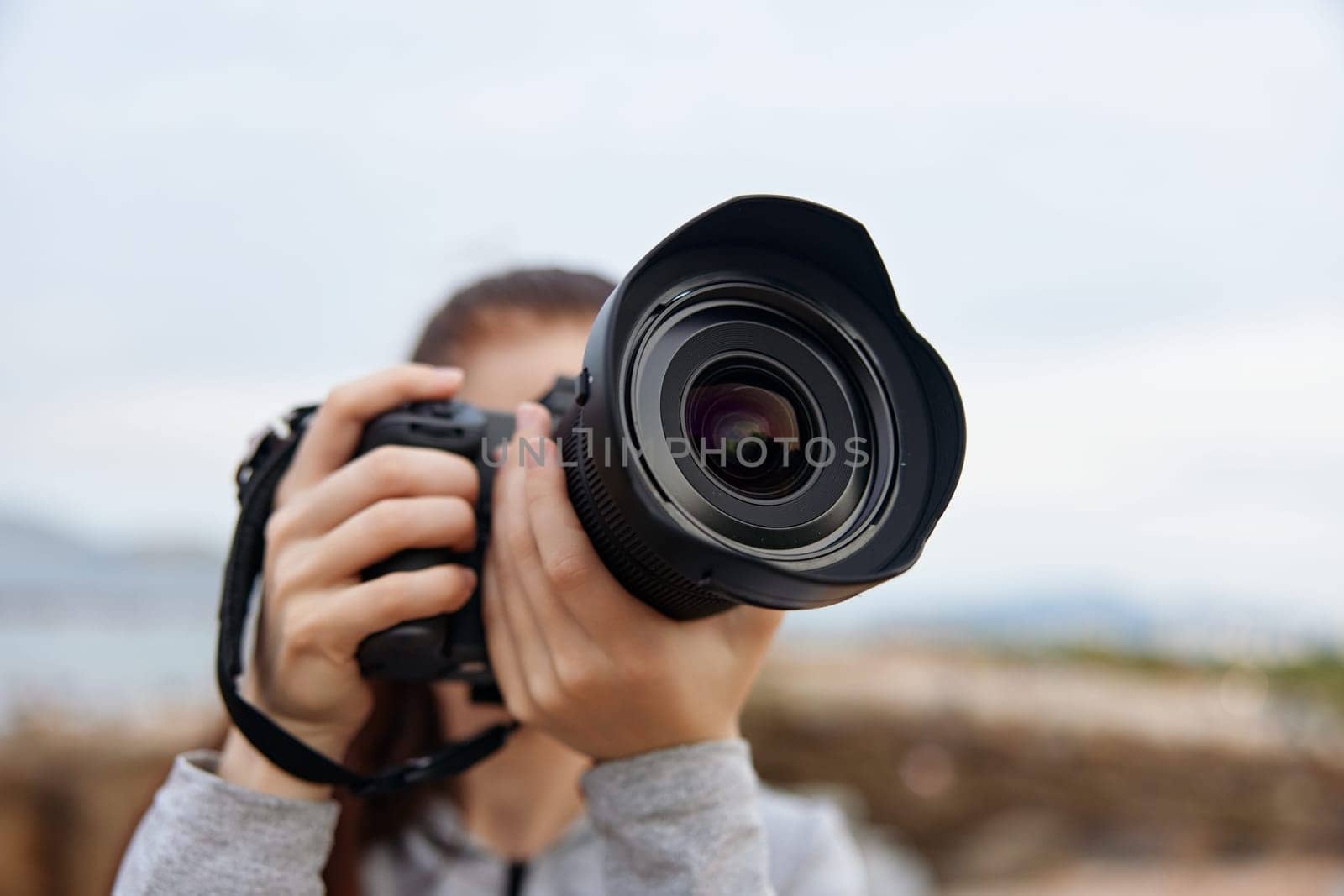 A female photographer passionately holding a camera outdoors against a natural backdrop, highlighting her love for photography with vibrant warm colors and an emotional connection to her art