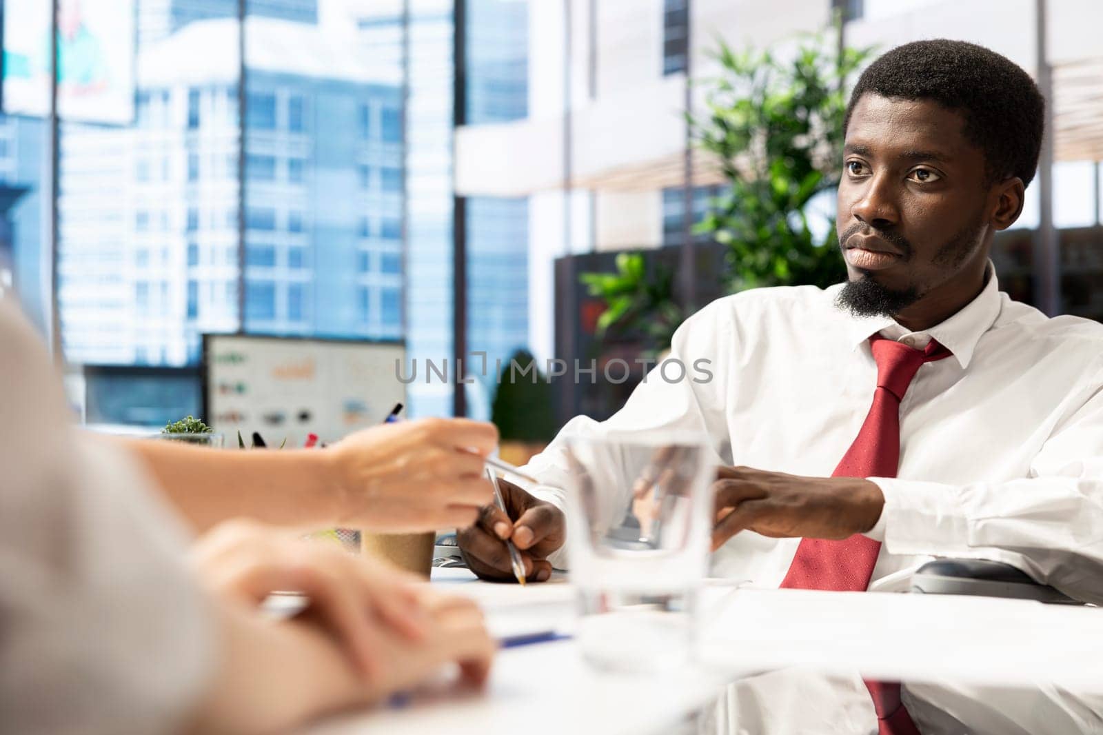 HR worker reviewing wheelchair user candidate, asking questions about qualifications, giving him application form. Person with paraplegia getting hired after proving enthusiasm for job opportunity