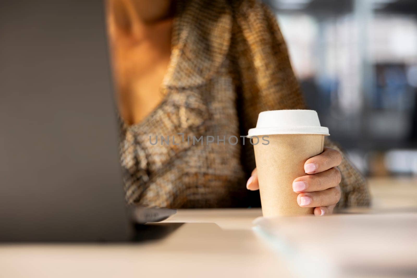 Successful woman in her workplace manages a variety of business tasks, drinking her morning coffee. Administrator focuses on business development, reports and project deadline. Close up.