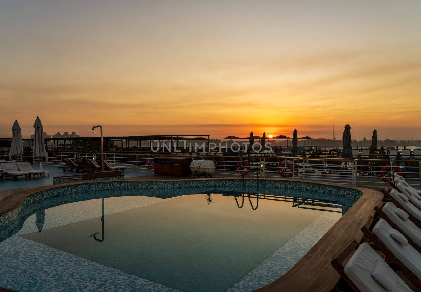Sun rises over the swimming pool on deck of Nile cruise boat docked alongside another ship in Edfu Egypt