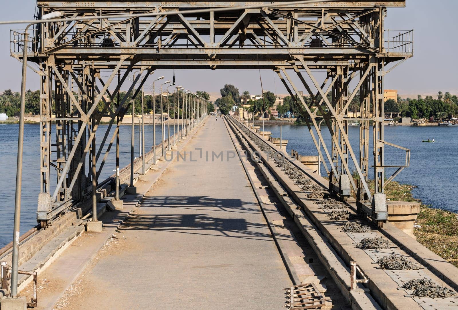Road across old Esna dam and lock across the Nile River with sandy hills of Sahara desert behind
