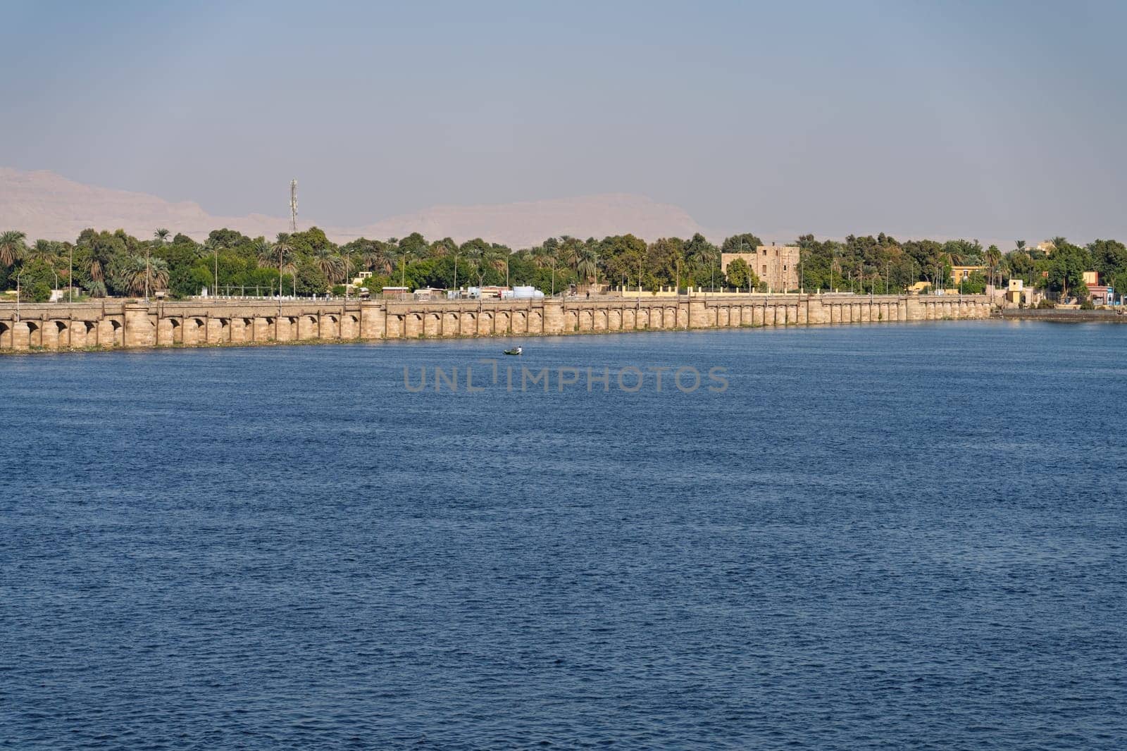 Old Esna dam and lock across the Nile River with sandy hills of Sahara desert behind