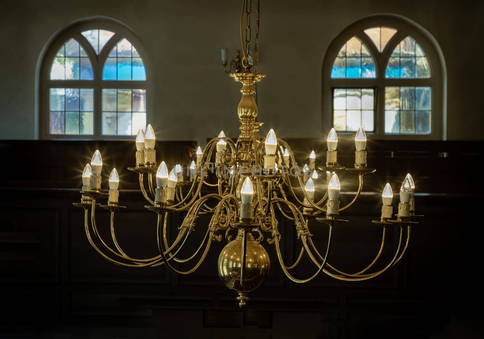 Royal Tunbridge Wells, UK - Apr 29, 2025 - Stunning view of Chandelier hanging from the ceiling with two glass windows in the background of The Church of King Charles the Martyr, is a Church of England parish church in Royal Tunbridge Wells, Kent, England. use it as your Wallpaper, Poster and Copy space, Selective focus.