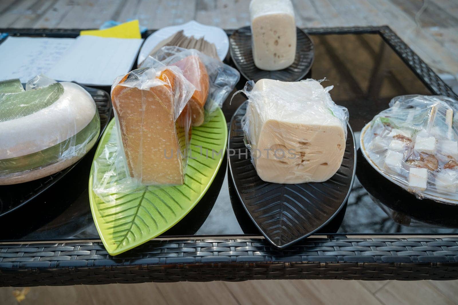 Farmers market display case featuring four wheels and wedges of artisan cheese. Each cheese has a different texture, rind, and color, offering a variety of flavors. Perfect for culinary or gourmet presentations.