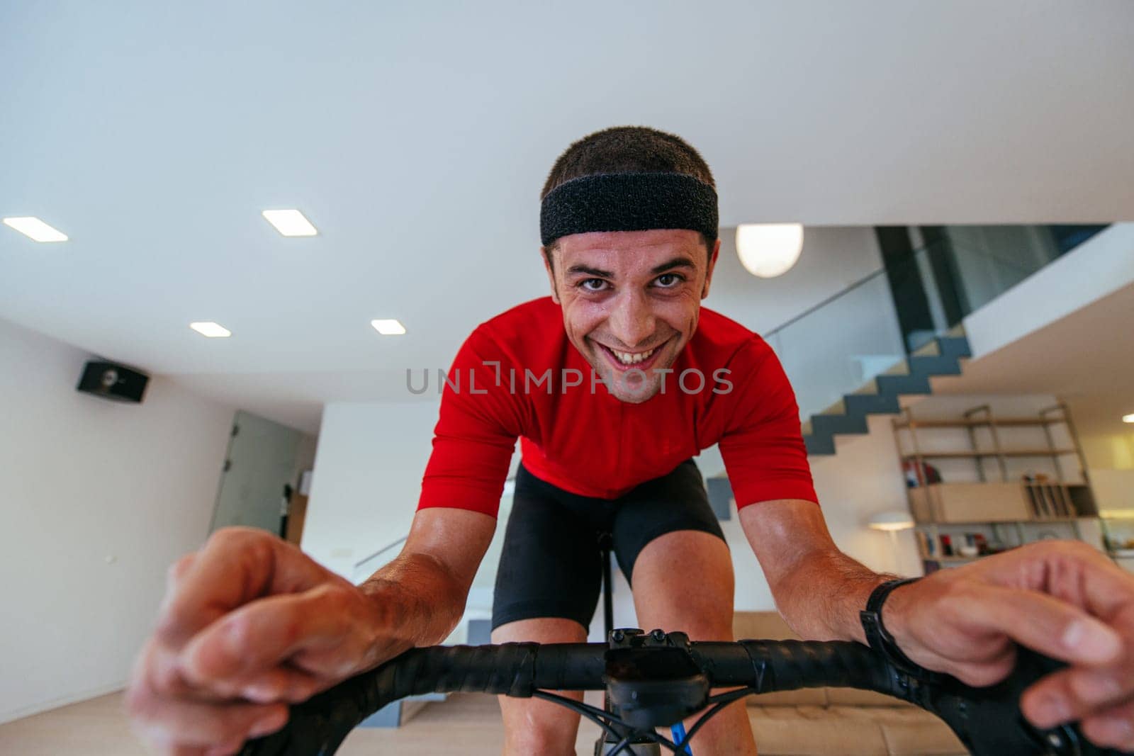 A triathlete riding a triathlon bike on a machine simulation in a modern living room. Training during pandemic conditions