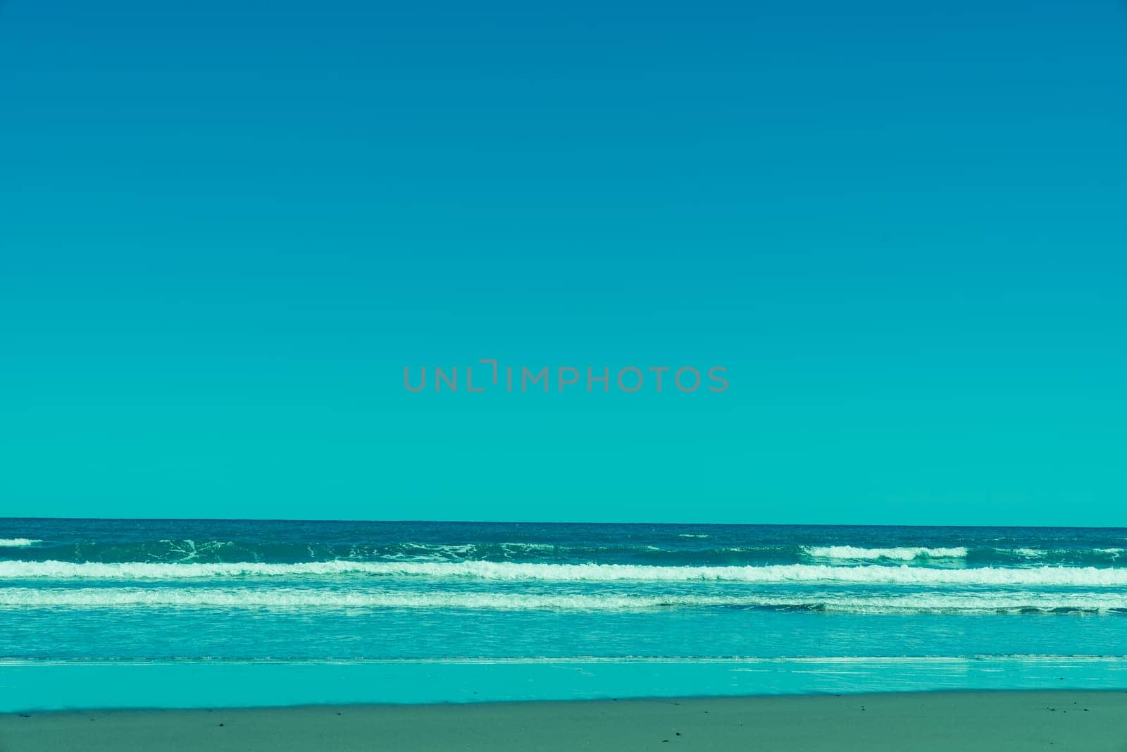 Opunake surf beach in retro with west coast black sand, blue sky and water.