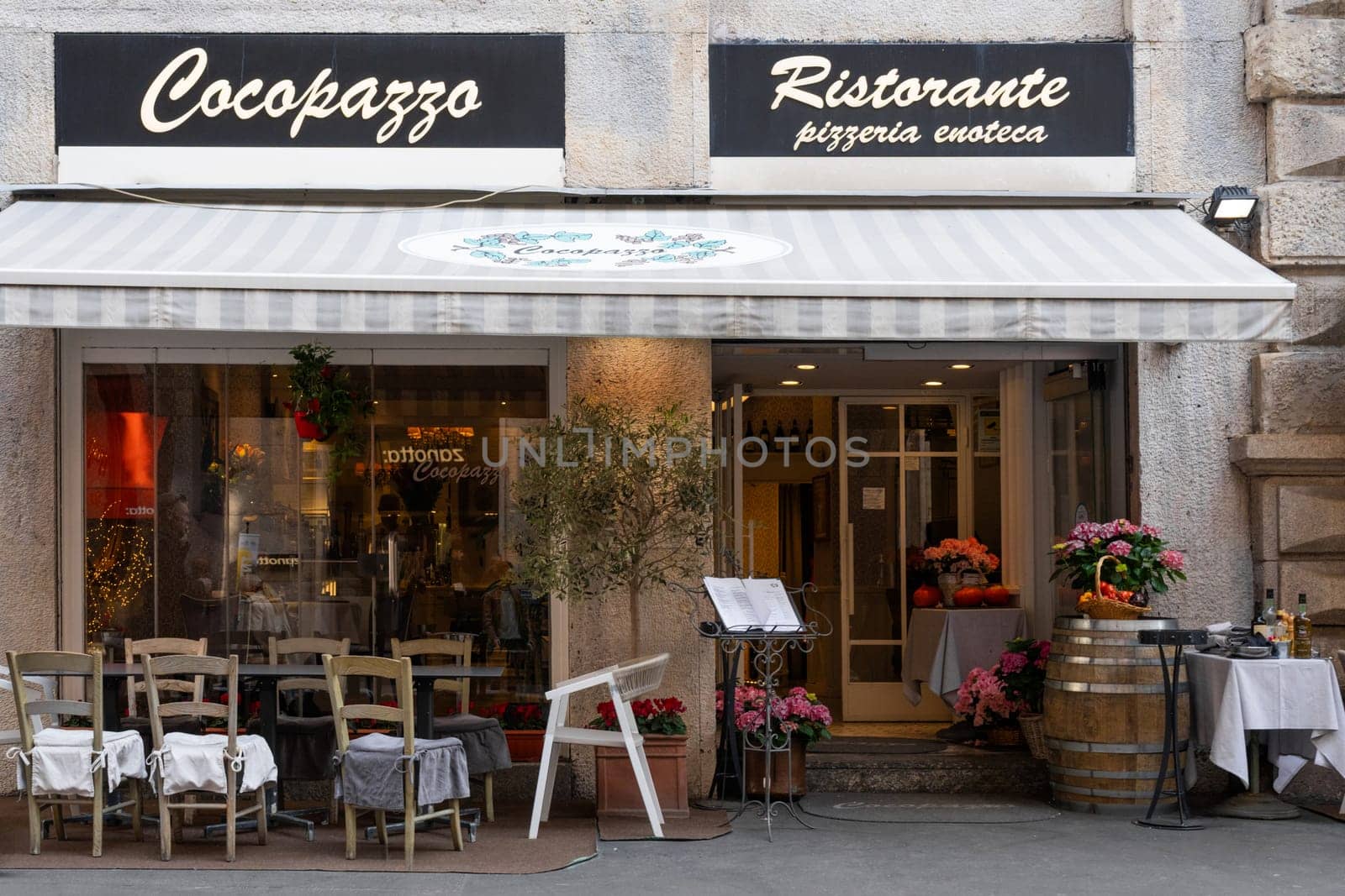Milan, Italy - April, 08, 2025: Cocopazzo Ristorante storefront in Milan. Italian eatery with outdoor seating, menu stand, flowers and rustic decor.
