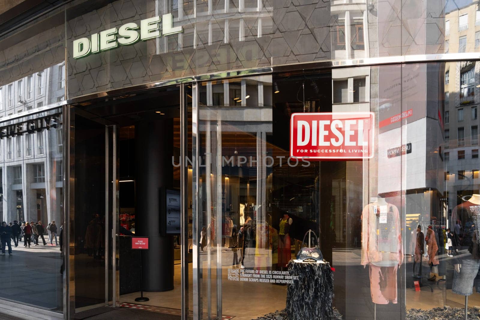 Milan, Italy - April, 08, 2025: Diesel store entrance in Milan. Glass facade with bold logo, reflections, mannequins in display. Urban fashion shopping scene.