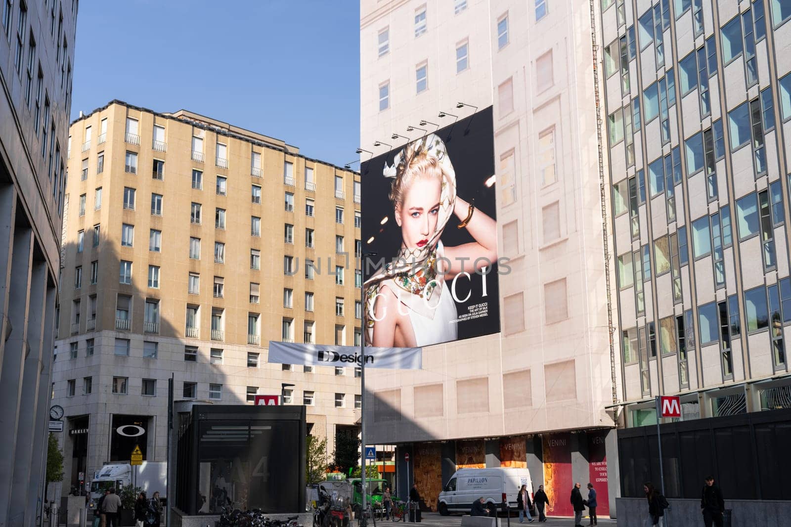 Milan, Italy - April, 08, 2025: Large Gucci fashion campaign billboard on city building facade in Milan near metro entrance. Street view with people walking.
