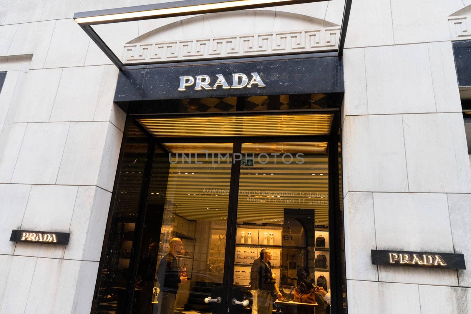 Milan, Italy - April, 08, 2025: Exterior of Prada boutique in Milan with glass doors and luxury interior visible. Elegant designer fashion storefront scene.