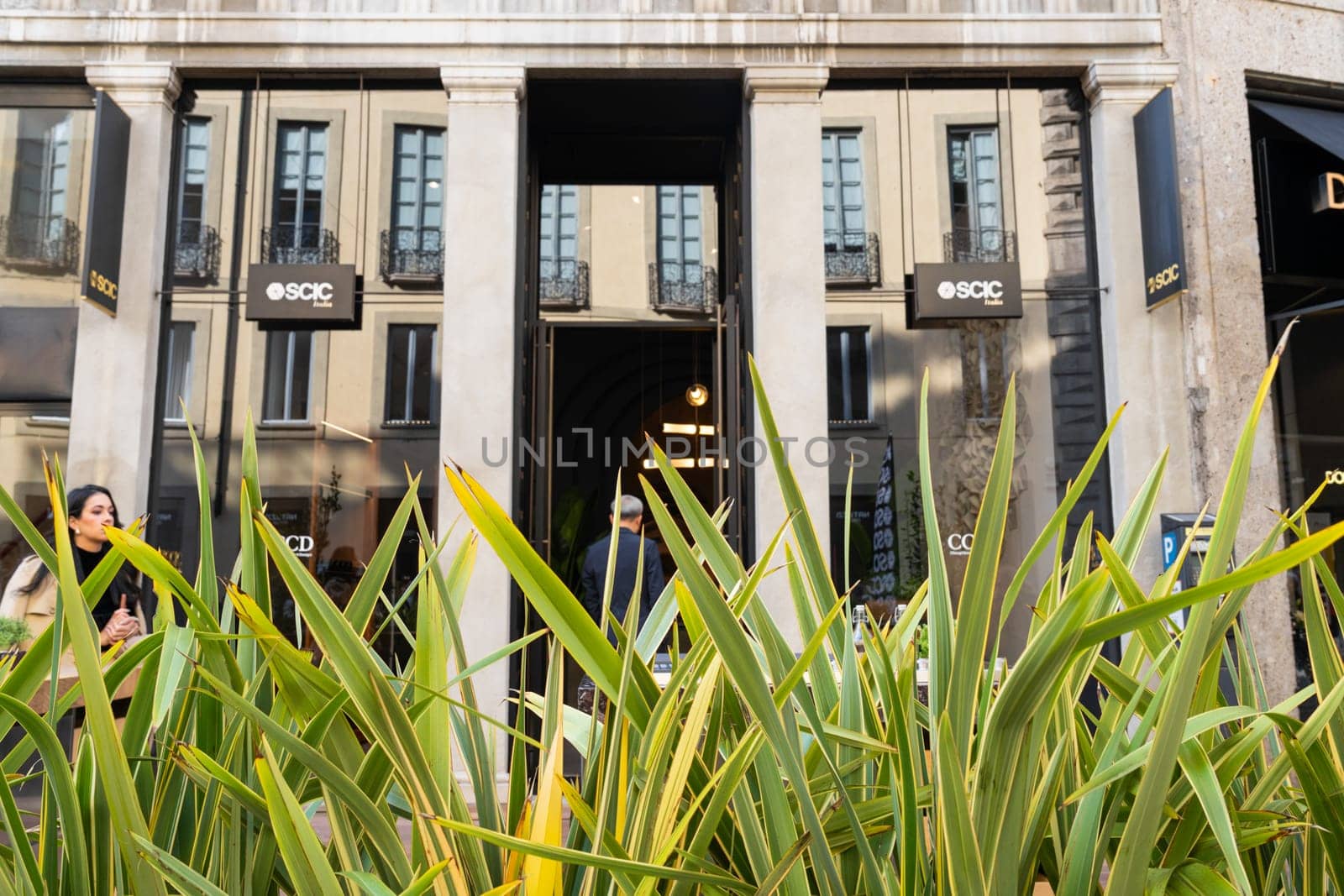 Milan, Italy - April, 08, 2025: SCIC Milano store exterior with green tropical plants in front. Brand logo visible on signage. Milan city architecture scene.