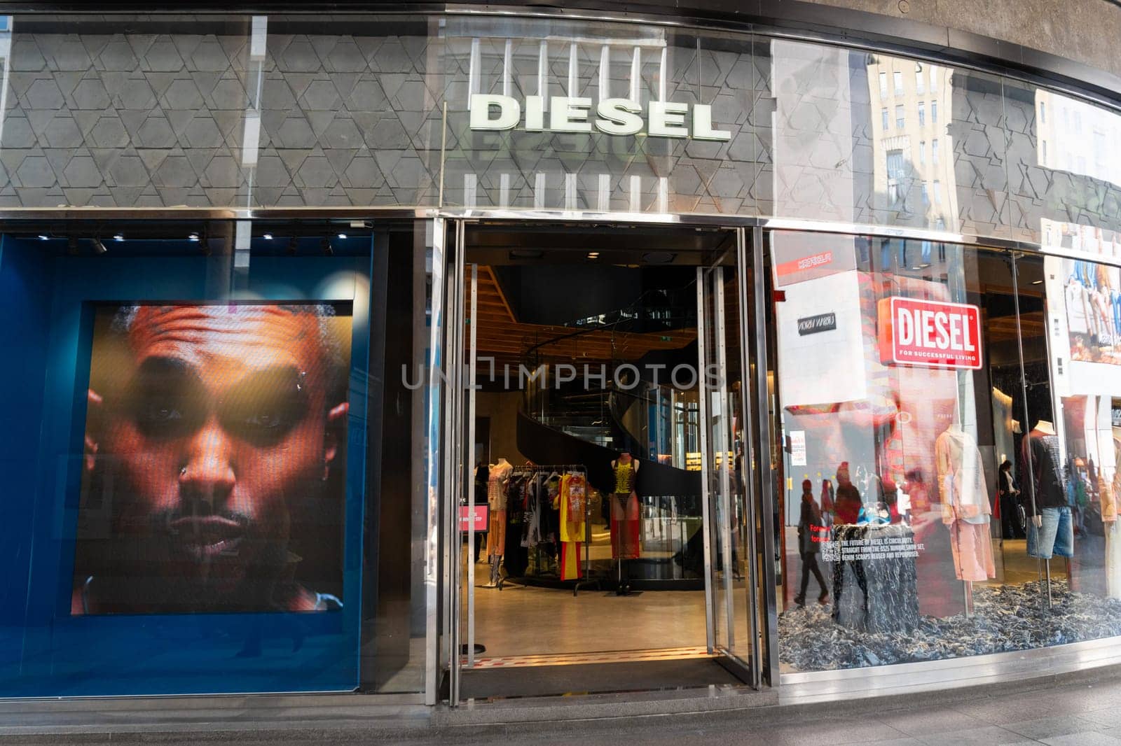 Milan, Italy - April, 08, 2025: Diesel fashion store entrance with illuminated signage, street-level view with interior display and branded visual screens.