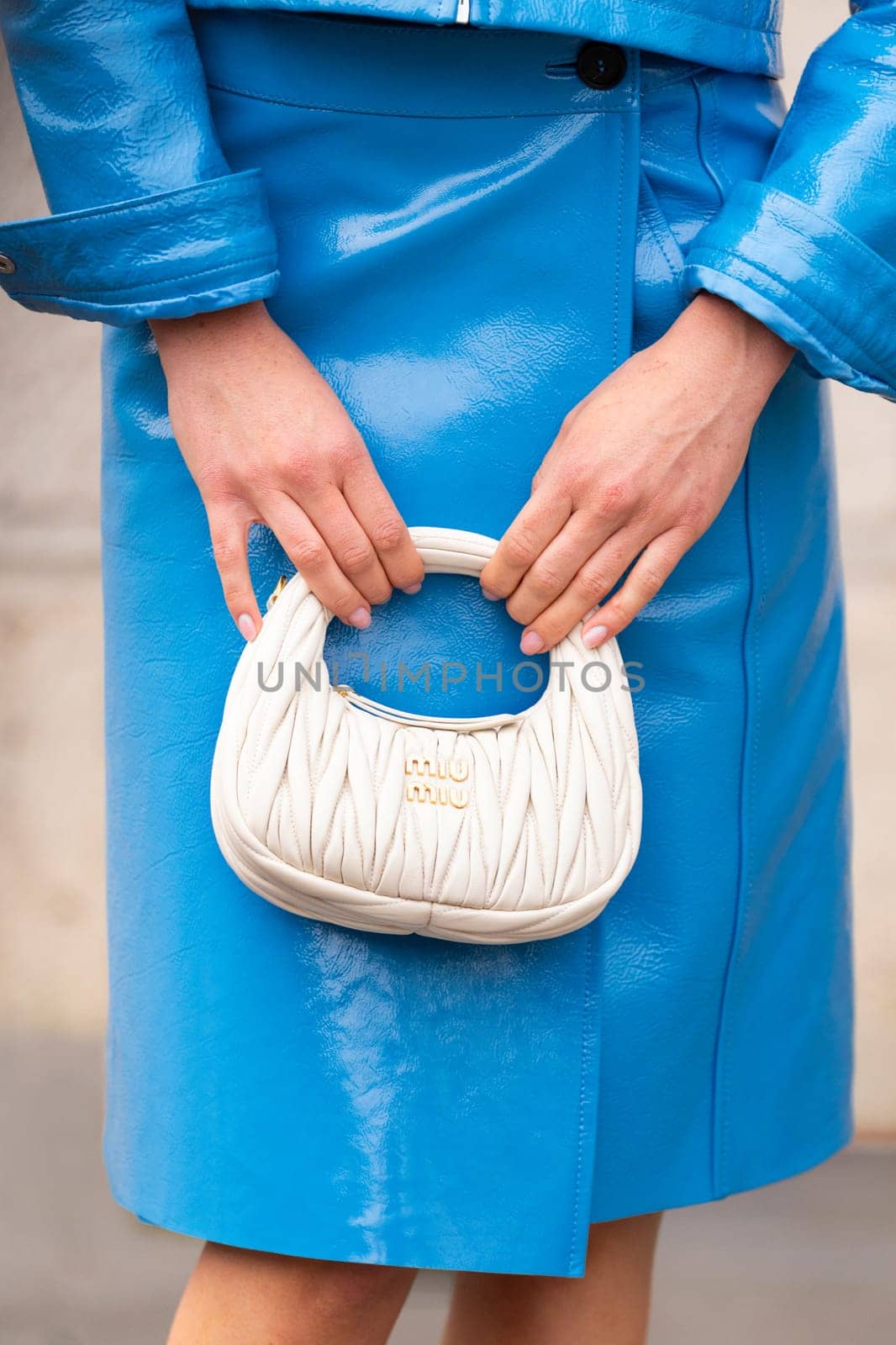 Paris, France - March 11, 2025: Woman wears quilted white Miu Miu mini bag with gold logo, paired. Street style outfit details.