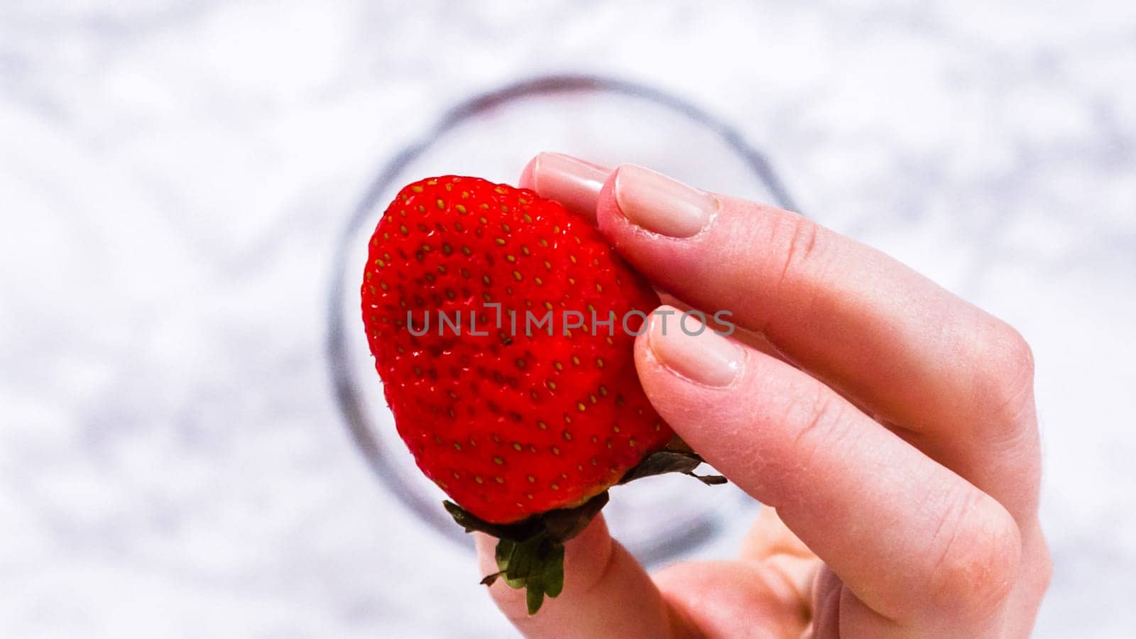 Flat lay. Strawberries, freshly washed and dried, are neatly stored in a glass bowl lined with a paper towel and securely covered with plastic wrap to maintain freshness.