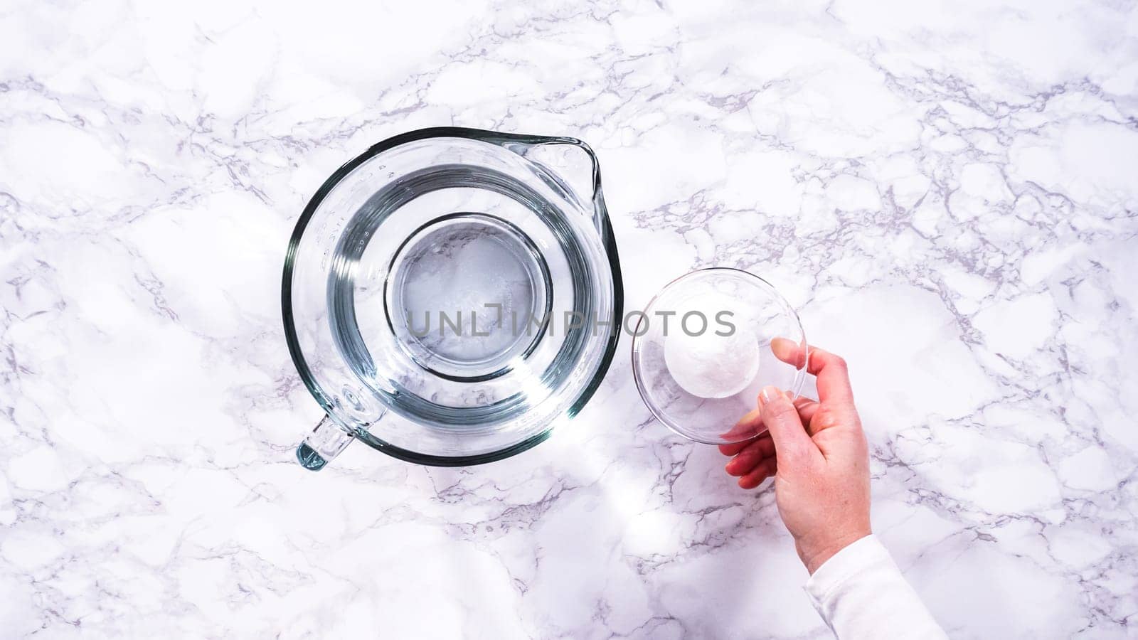Flat lay. A spacious glass mixing bowl filled with water sits prepared to gently cleanse a batch of ripe strawberries, ensuring they are pristine before drying or storage.