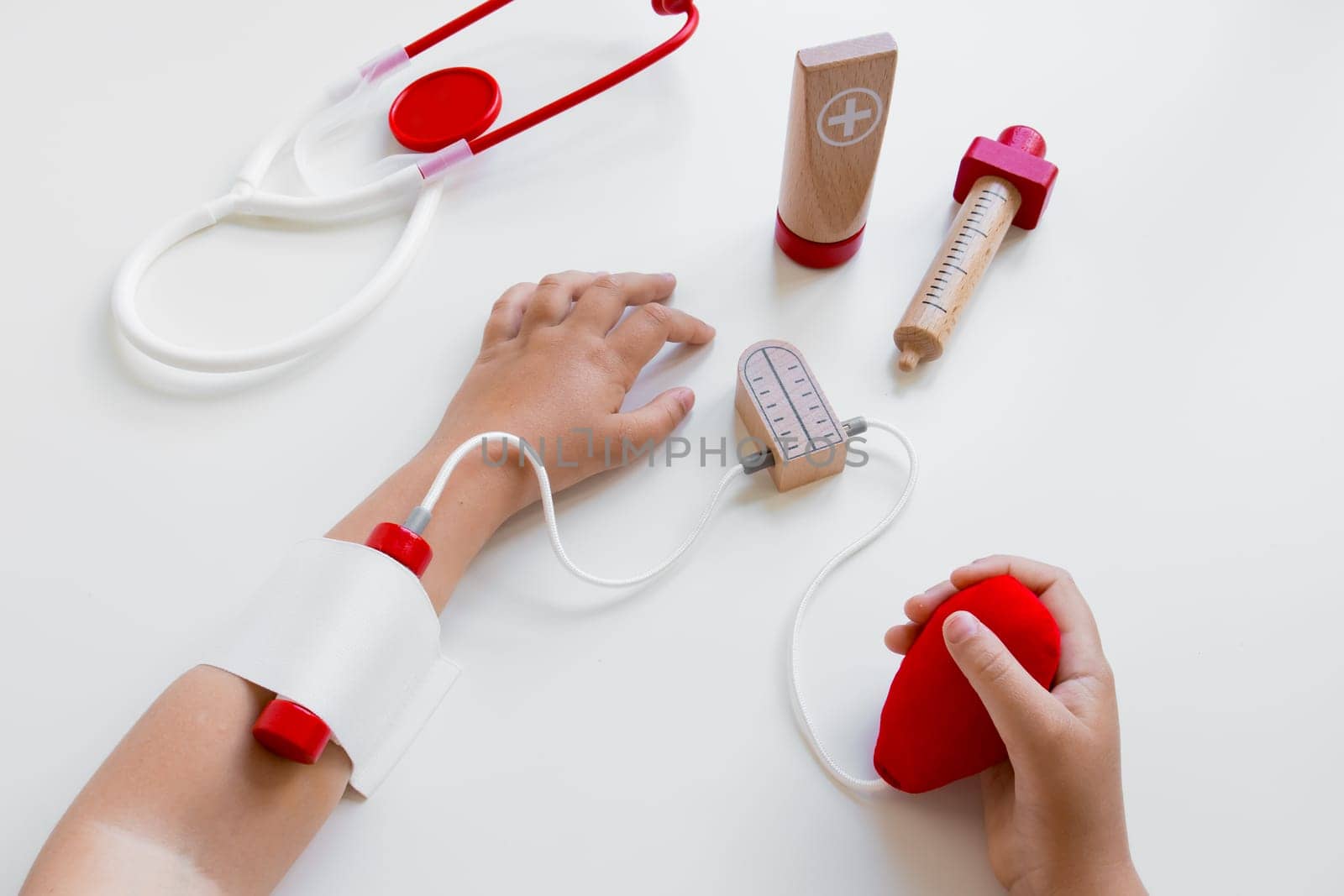 Child hands playing with toy medical set on white background.