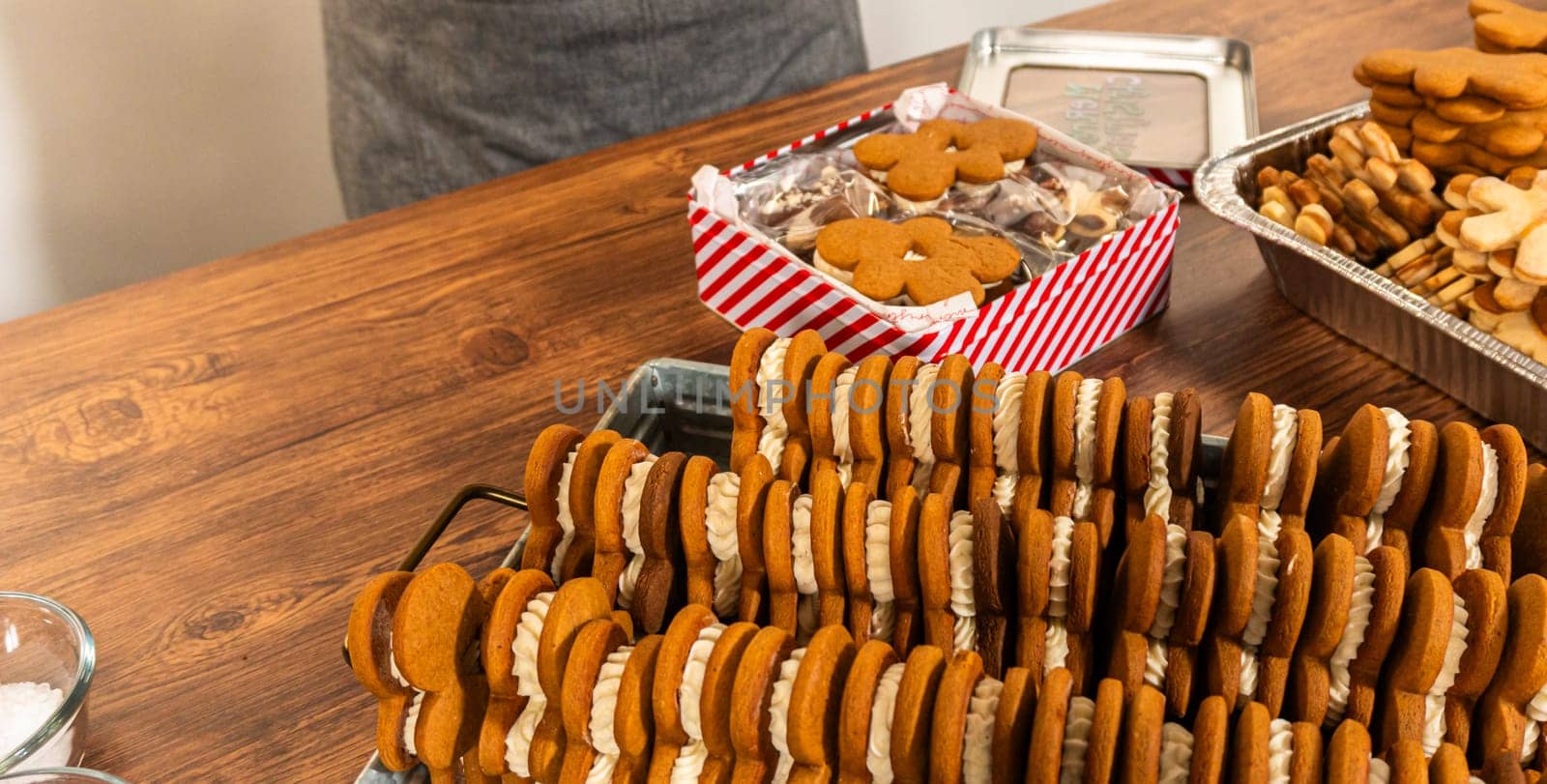 Making gingerbread man cookie sandwiches filled with eggnog buttercream, arrayed on a rustic wooden table, ideal for heartfelt Christmas gifting.