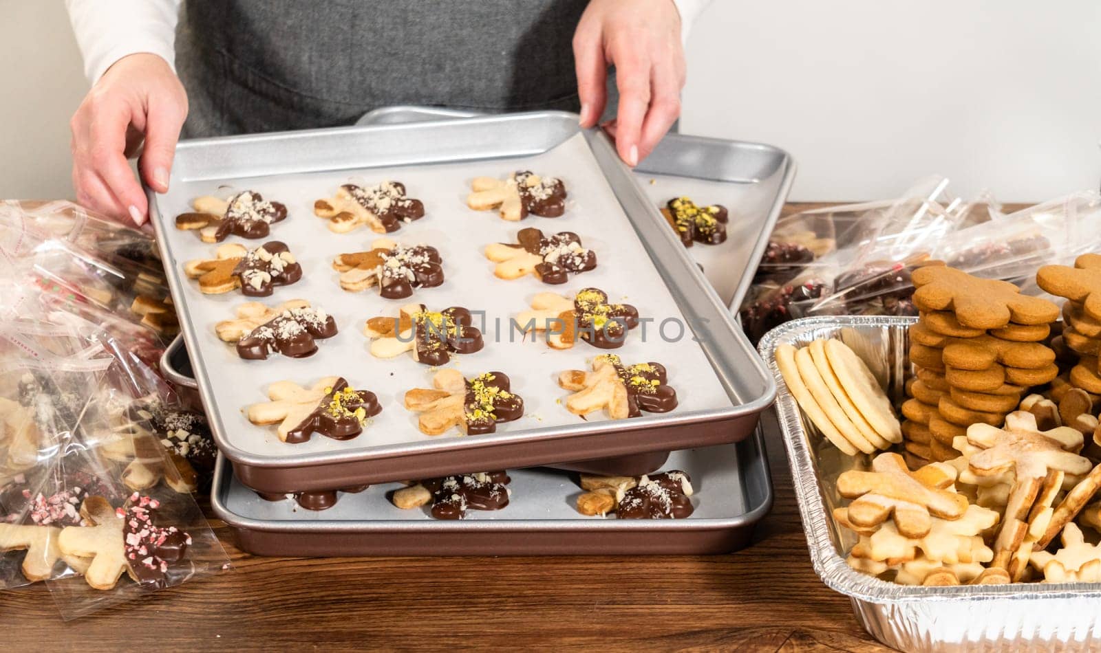 Carefully packaging Christmas cutout cookies, half-dipped in chocolate and presented in clear cellophane wrapping, perfect for festive gifting.