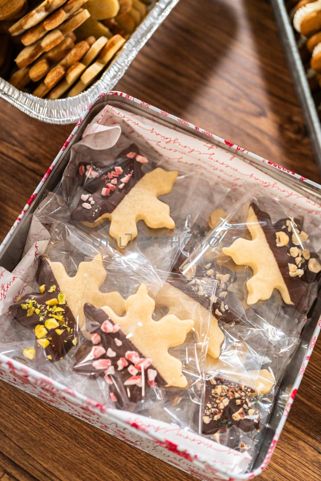 Lovingly homemade gingerbread and sugar cookies, half-dipped in rich chocolate, nestled in decorative Christmas tin boxes perfect for seasonal gifting.