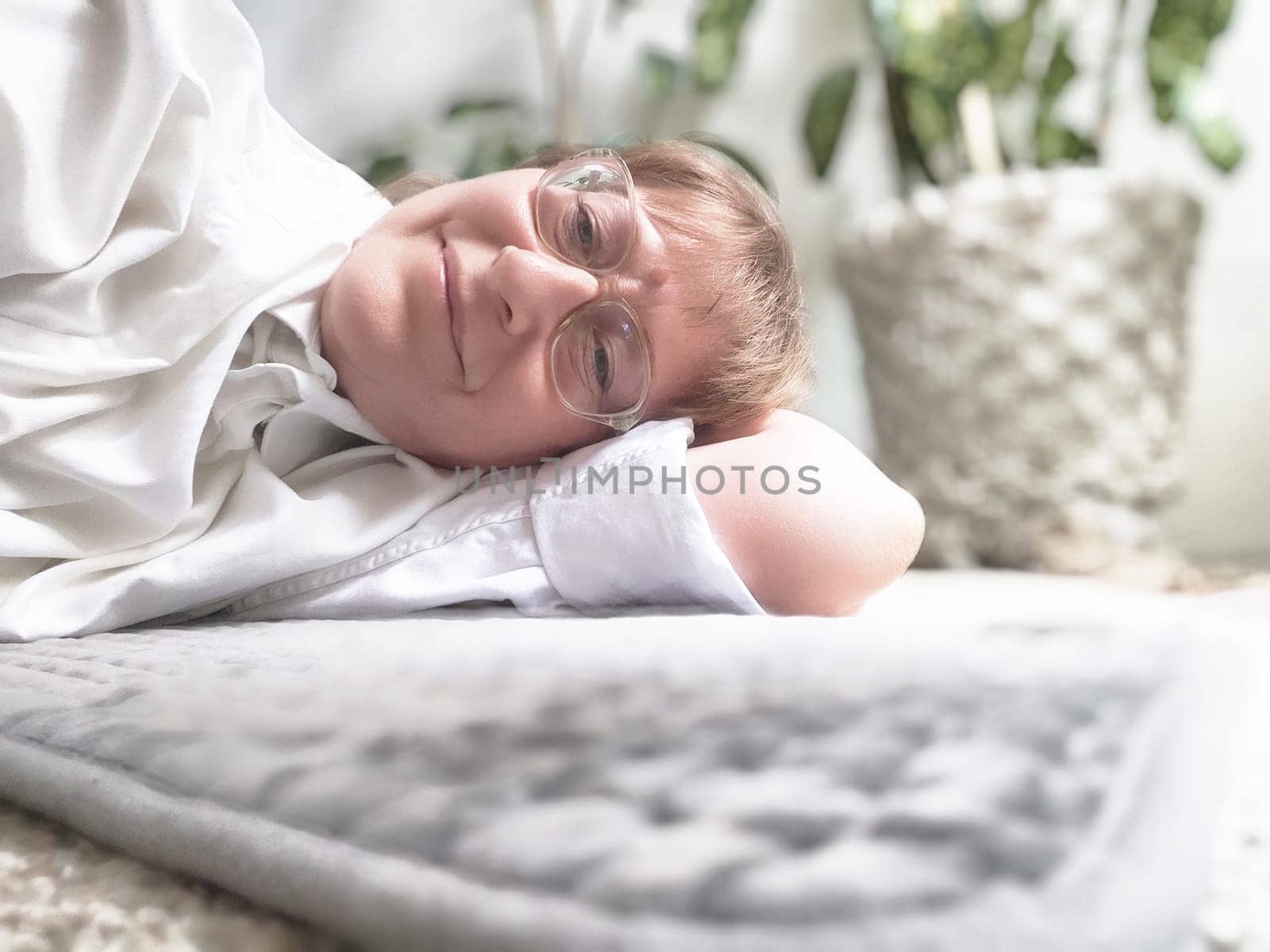 Person lies comfortably on an electric heating pad, surrounded by indoor plants, enjoying a moment of relaxation and warmth.