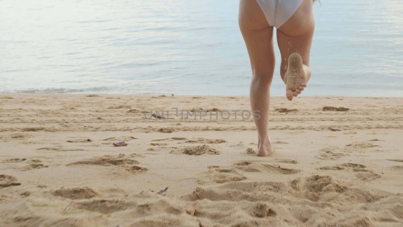 Back view, Young beautiful woman wearing bikini swimsuit running into tropical on sand beach to water, Happy Asian female have fun she run holiday outside, Summer travel vacation concept
