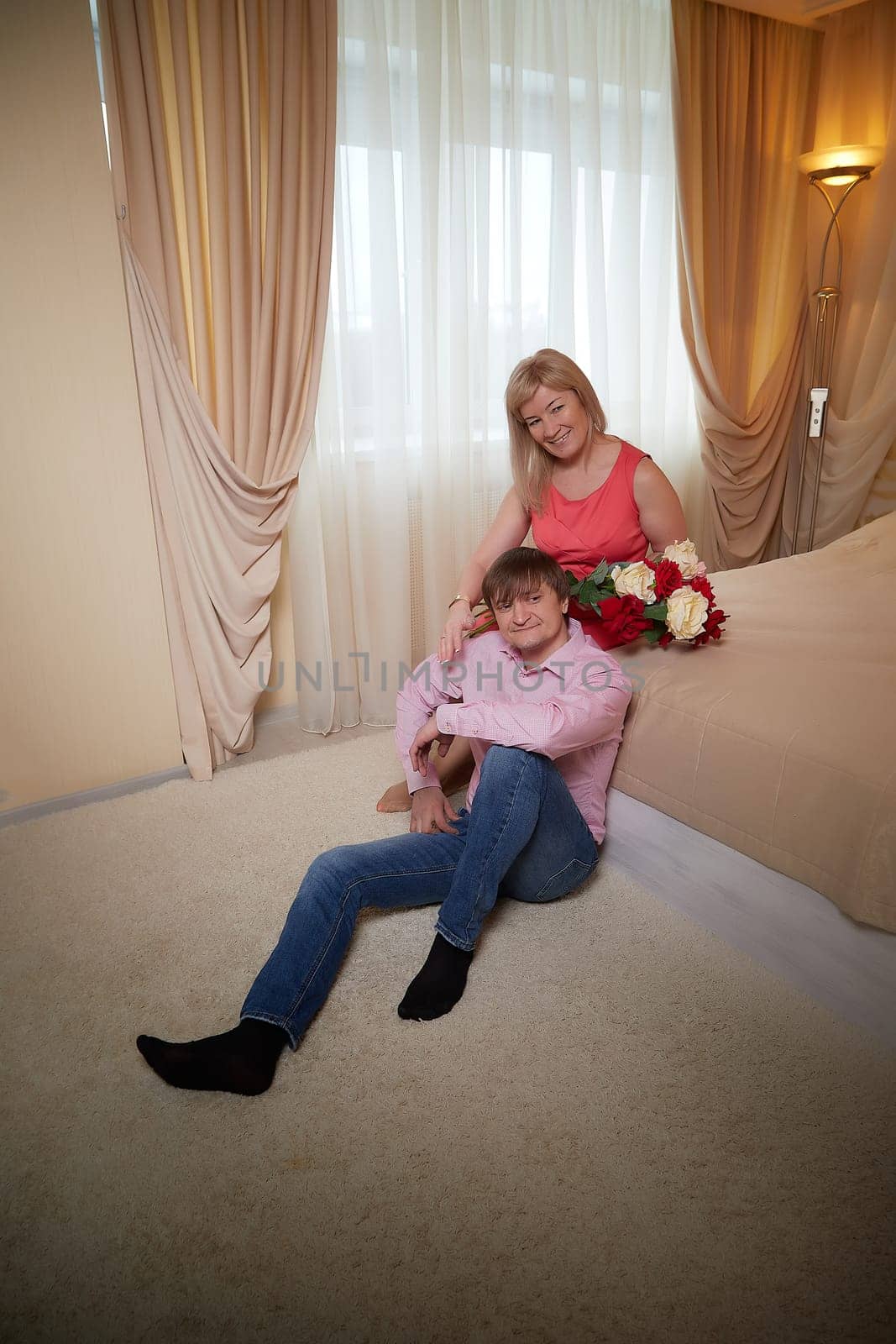 Middle-aged couple celebrates their love with a romantic photo shoot, surrounded by flowers in a hotel setting.