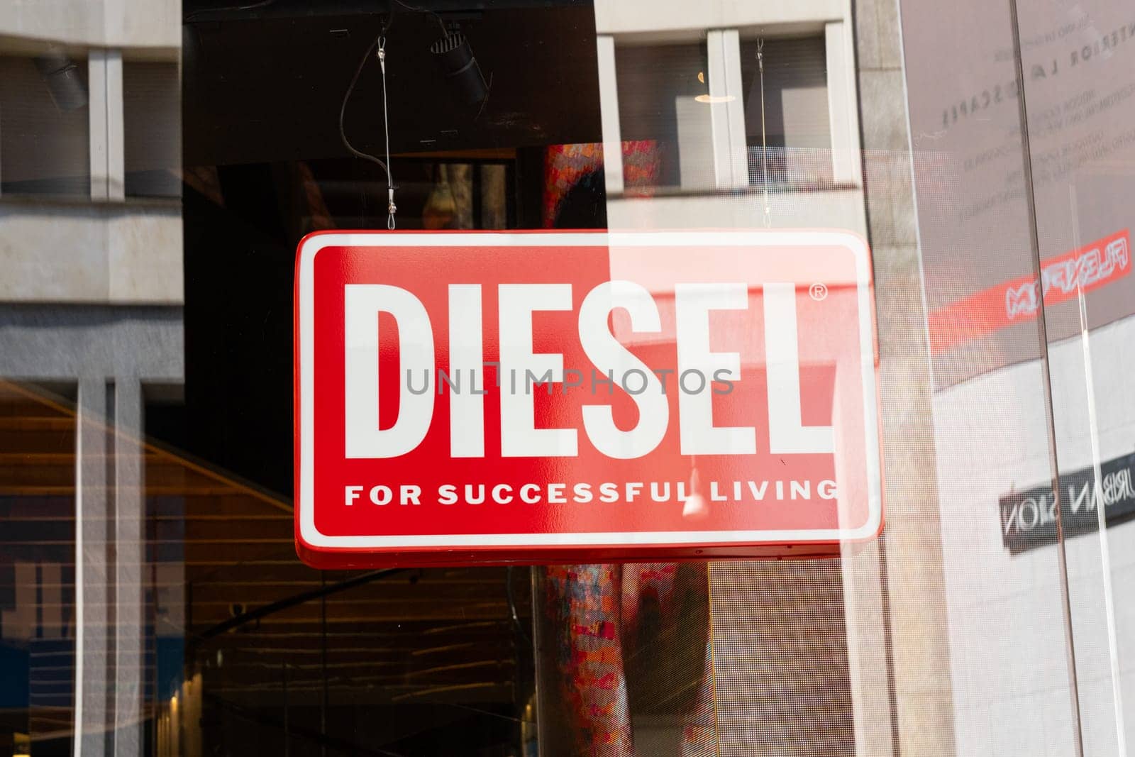 Milan, Italy - April, 08, 2025: Diesel red logo signage. Bold white text For Successful Living on glass storefront in Milan. Closeup urban retail branding.