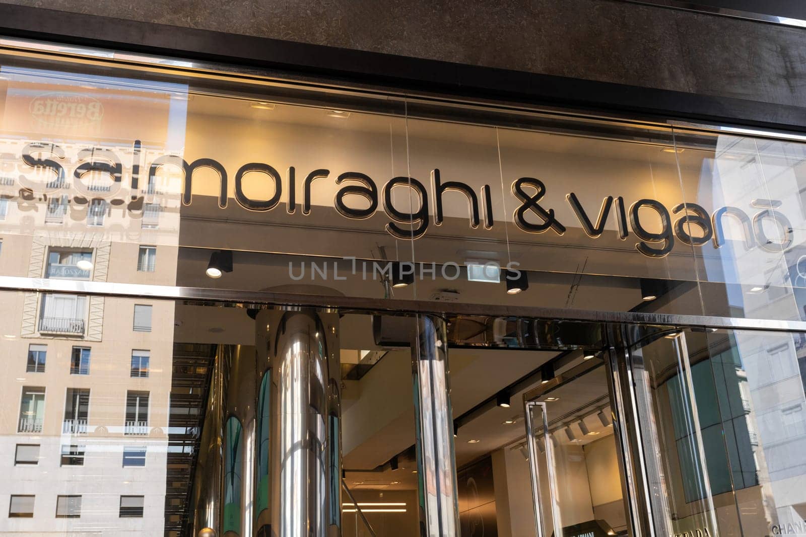 Milan, Italy - April, 08, 2025: Closeup of Salmoiraghi and Vigano eyewear store entrance with chrome columns and brand logo. Milan, Italy. Glass and metal facade.