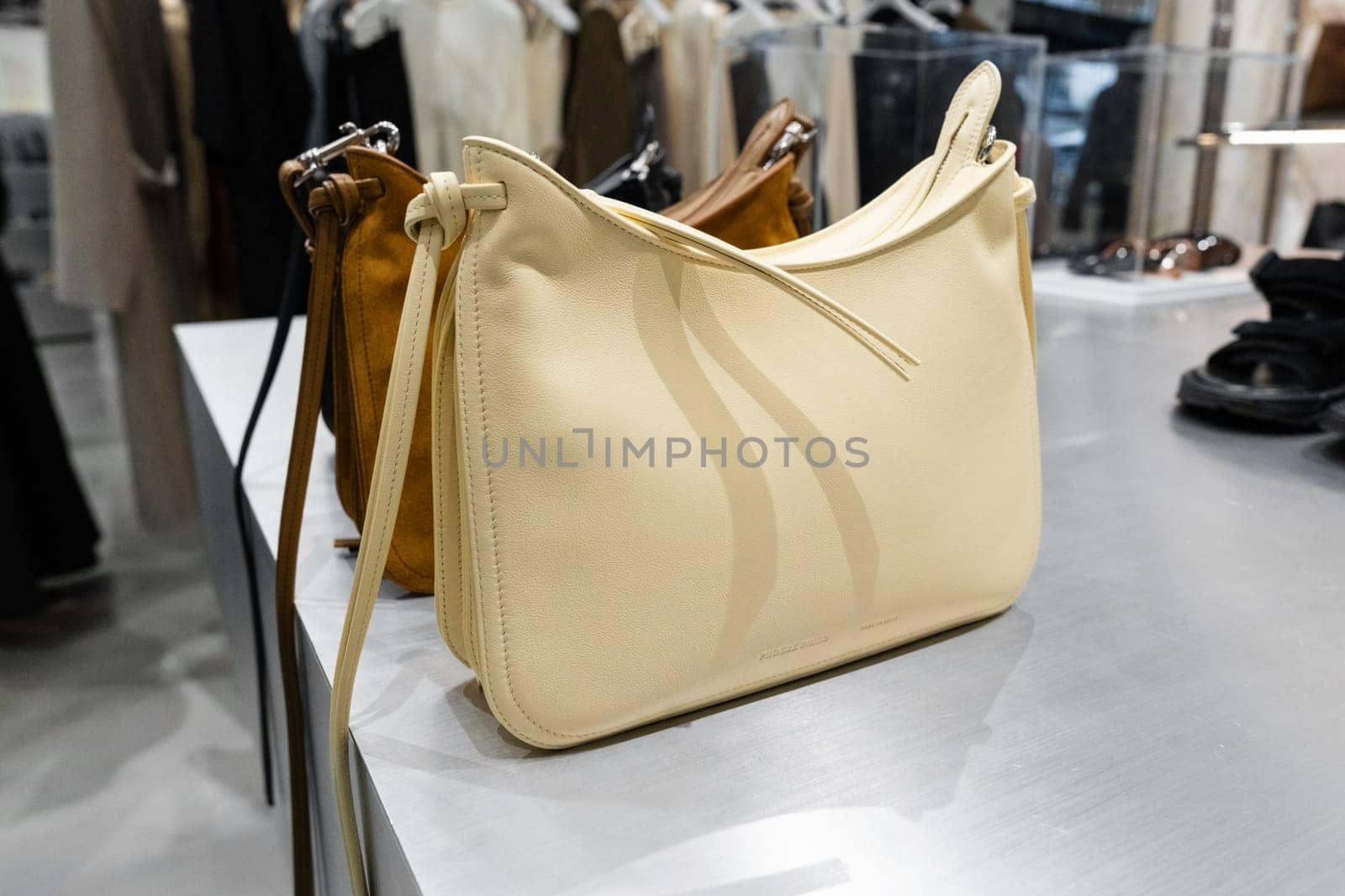 Milan, Italy - April, 08, 2025: Cream leather Phoebe Philo shoulder bag on metal counter. Designer fashion accessories display inside Milan boutique. Close up retail view.