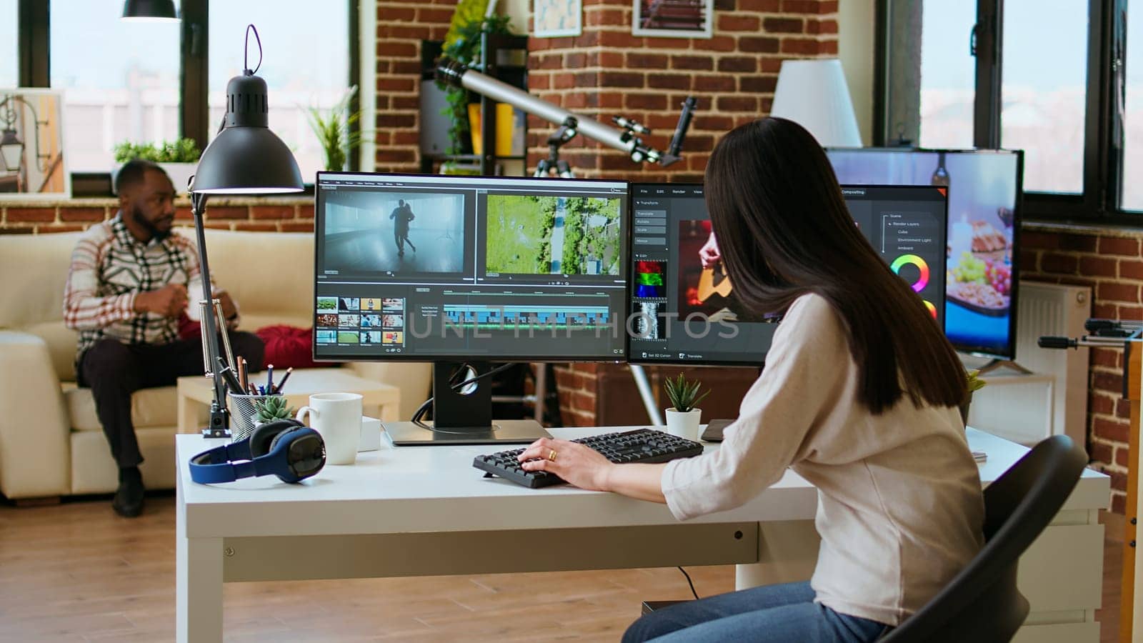 Asian woman editing a music video in her living room studio, multitasking between timeline editing and color grading. Professional workspace features tech tools for multimedia creation. Camera A.