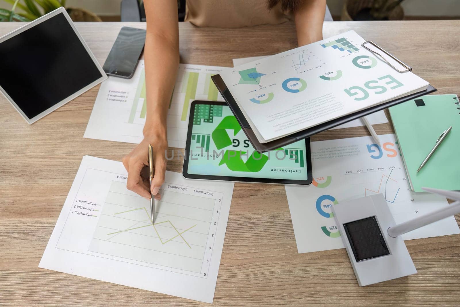 An analytical individual reviews ESG sustainability data and charts on a clipboard, emphasizing sustainable practices and metrics.