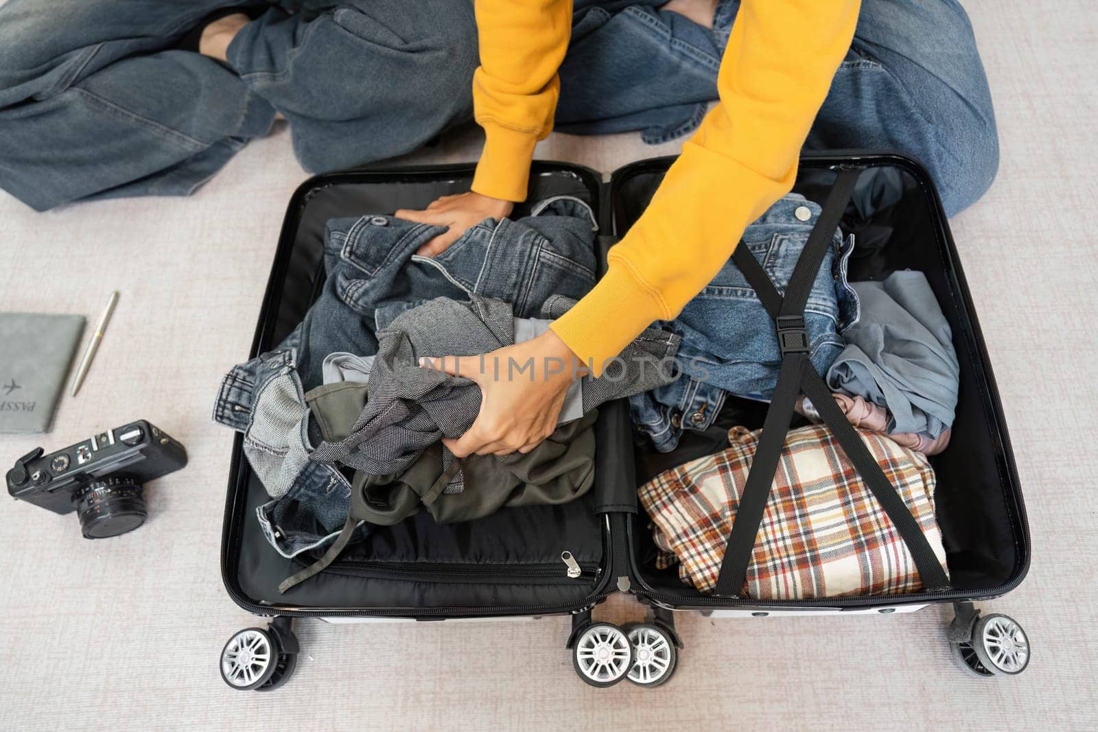A young woman organizing her clothes into a suitcase while preparing for her travel adventure, showcasing excitement and anticipation.