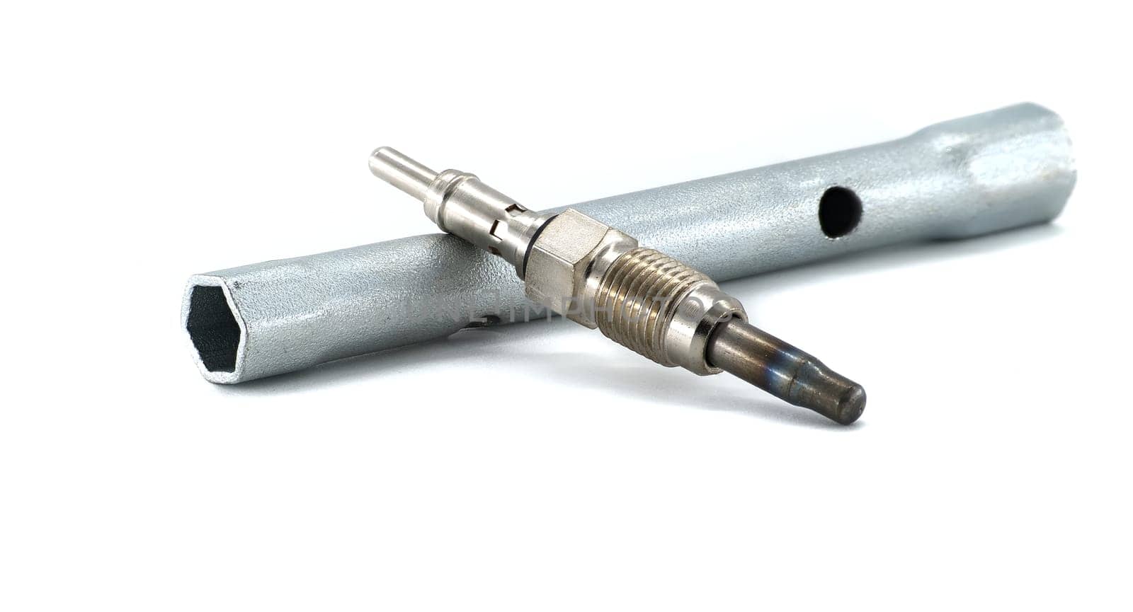 Close-up of a diesel engine glow plug with a socket tool used for installation or maintenance, against a white background.