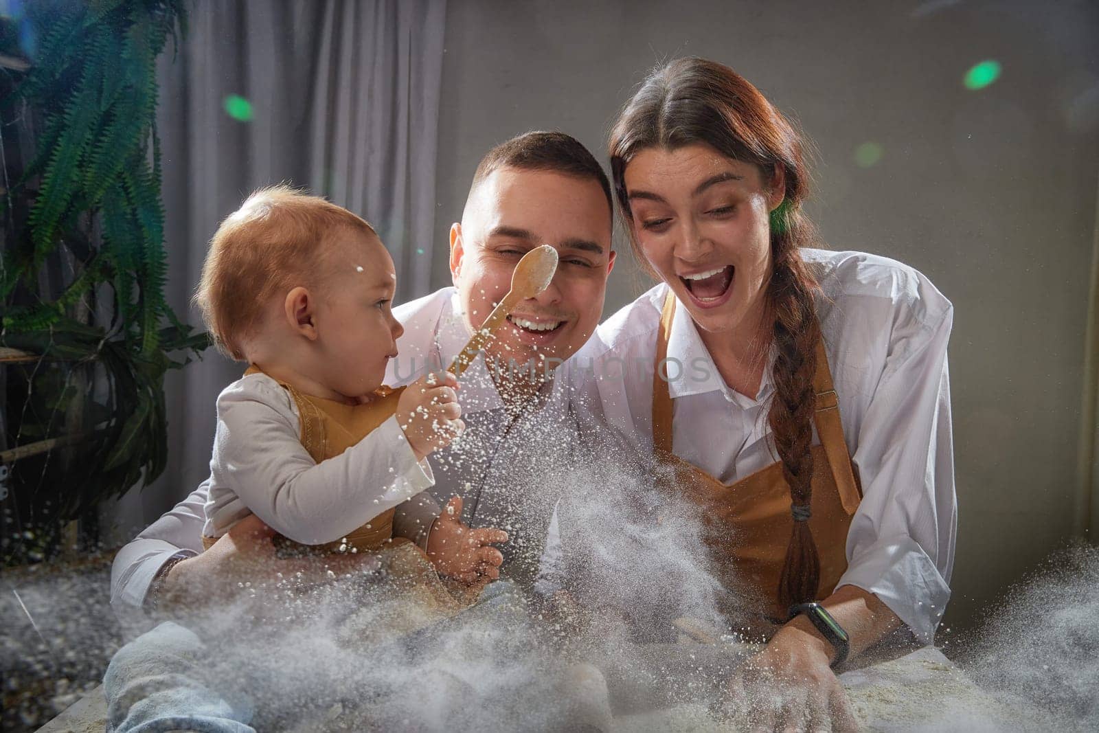 A family enjoys a fun cooking session, playfully covered in flour while engaging with their little ones in warm kitchen