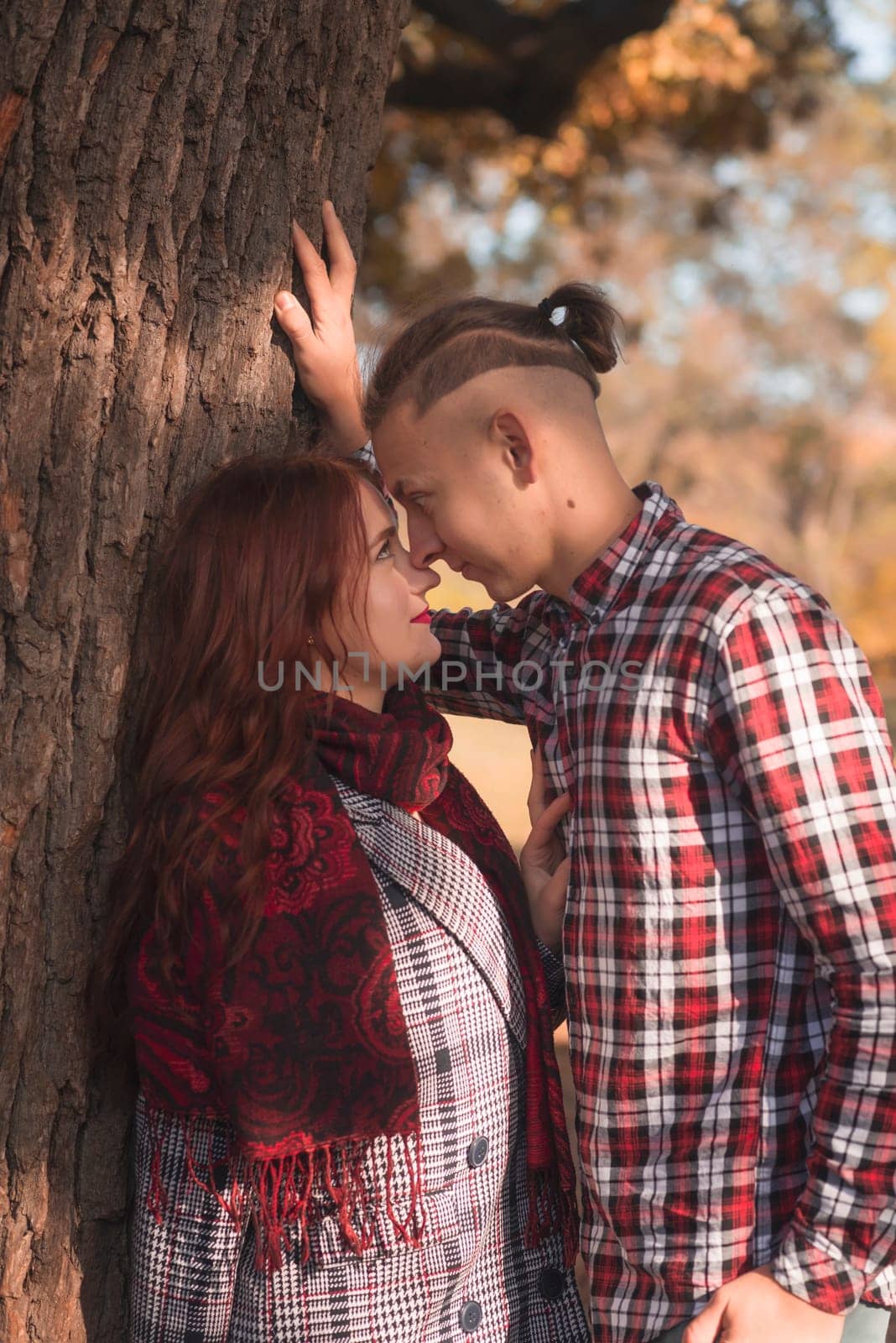 young couple in love walking and having fun in autumn park. they look at each other, against the background of autumn trees. concept of romance, falling in love, relaxation