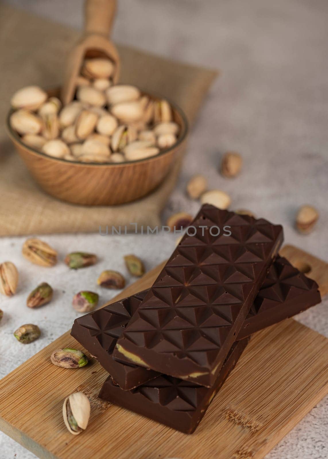 Gourmet chocolate mixed with crunchy kadaif pistachio pieces is beautifully presented on a wooden board, making a perfect treat in Dubai's culinary scene.