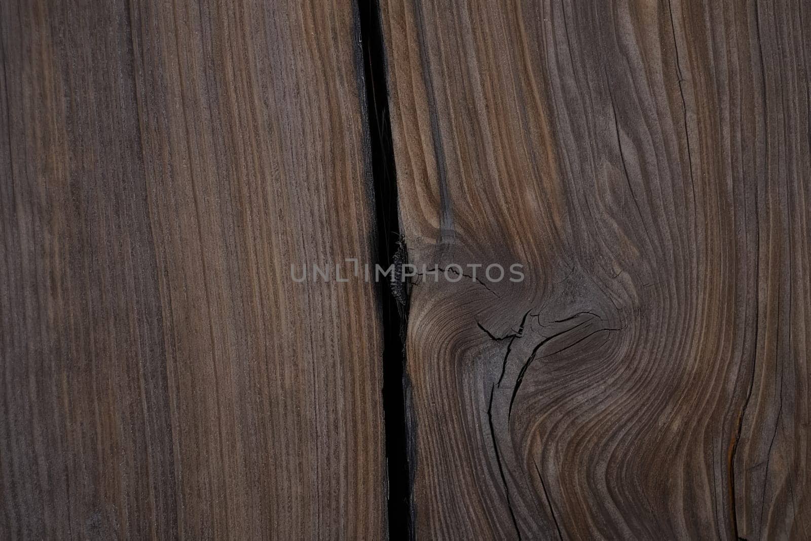 Detailed close up of a wooden surface featuring a noticeable crack and intricate grain patterns. The rich textures highlight the woods natural beauty and uniqueness.