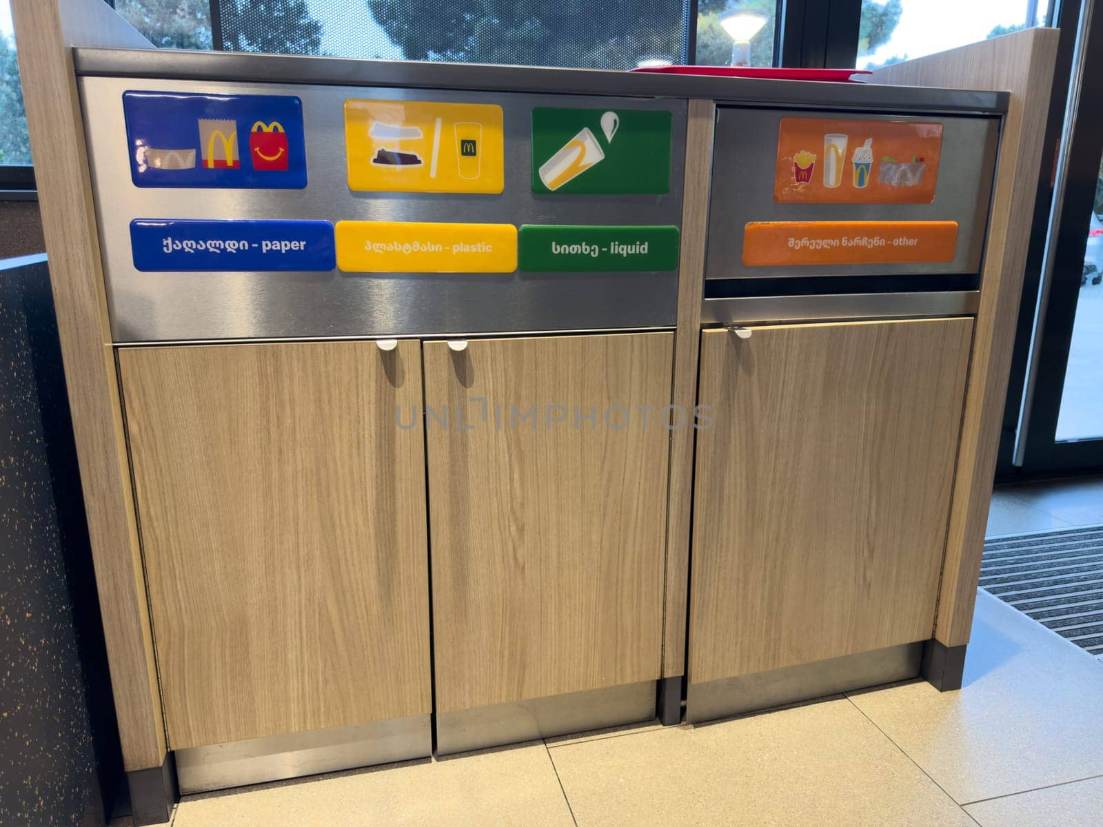 Tbilisi, Georgia, April 13, 2025: Waste sorting bins inside a McDonalds restaurant with labels for paper, plastic, liquid, and other waste in English and Georgian