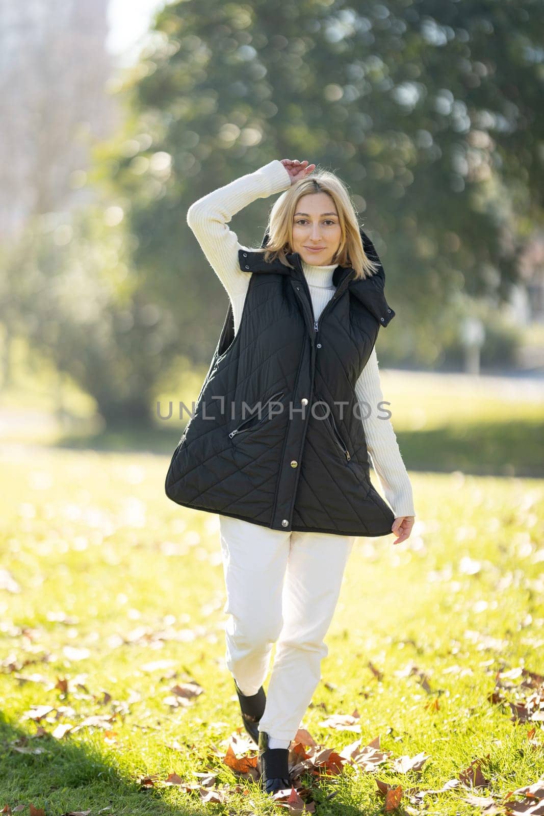 Young woman wearing casual clothing enjoying a walk in a park during a sunny autumn day