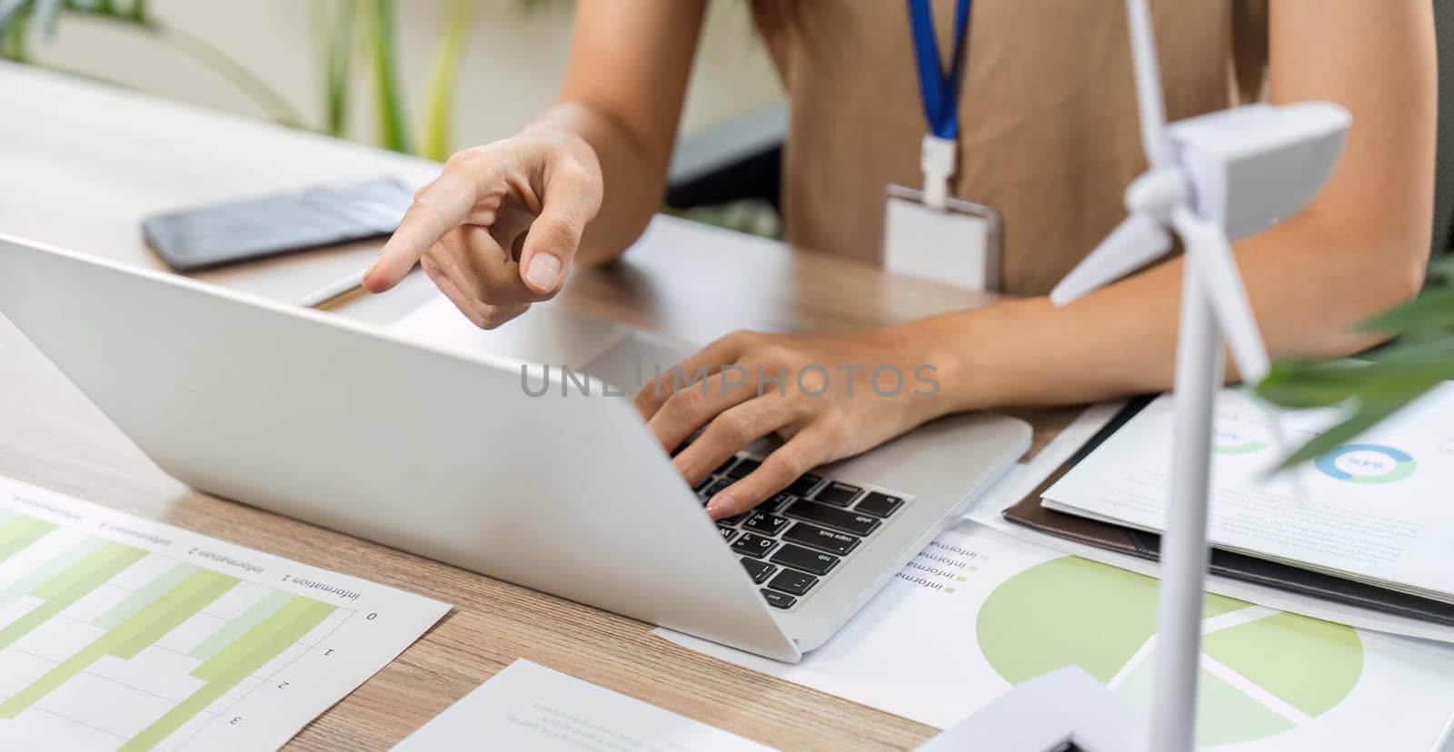 A focused ESG sustainability consultant pointing at a laptop screen, analyzing data relevant to environmental and social governance.