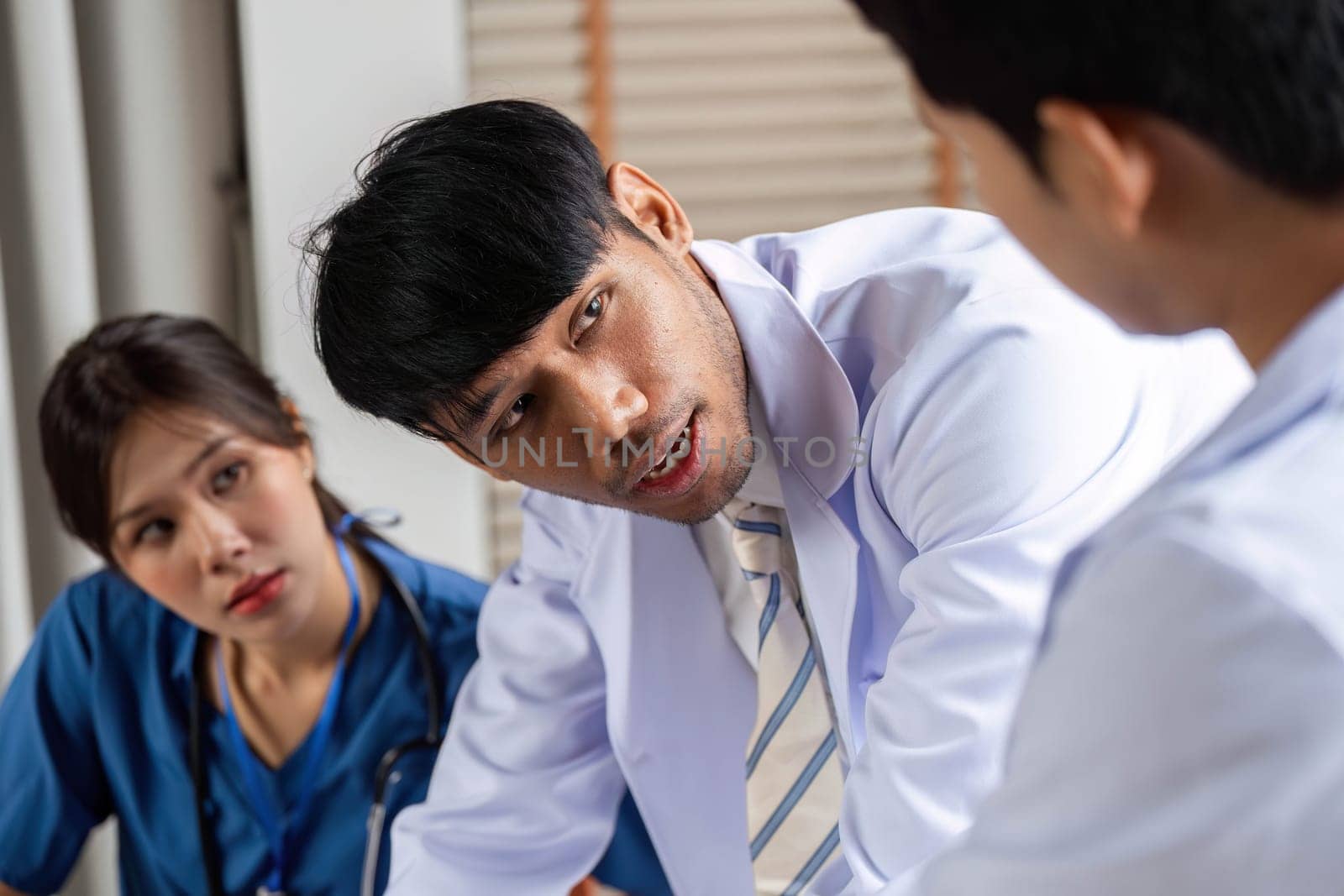 A doctor engaging with a diverse medical team while discussing treatment plans and patient care strategies in a clinic setting.
