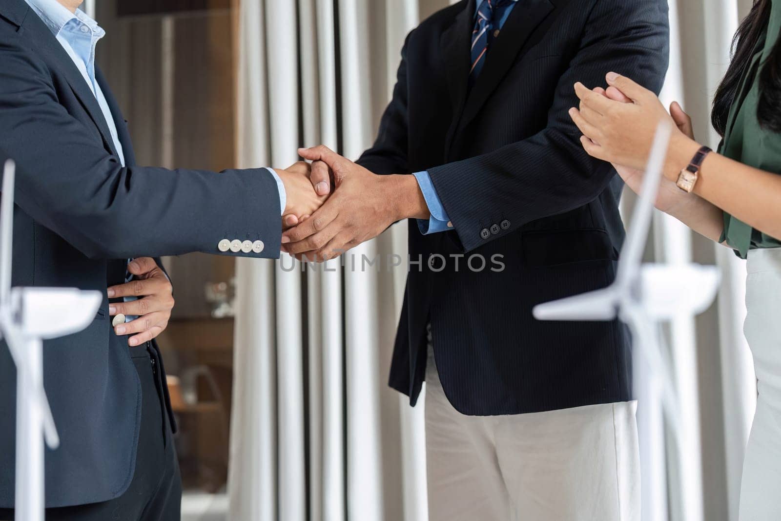 A diverse team signifies a successful ESG partnership with a handshake in a modern office, emphasizing collaboration and mutual goals for sustainability.