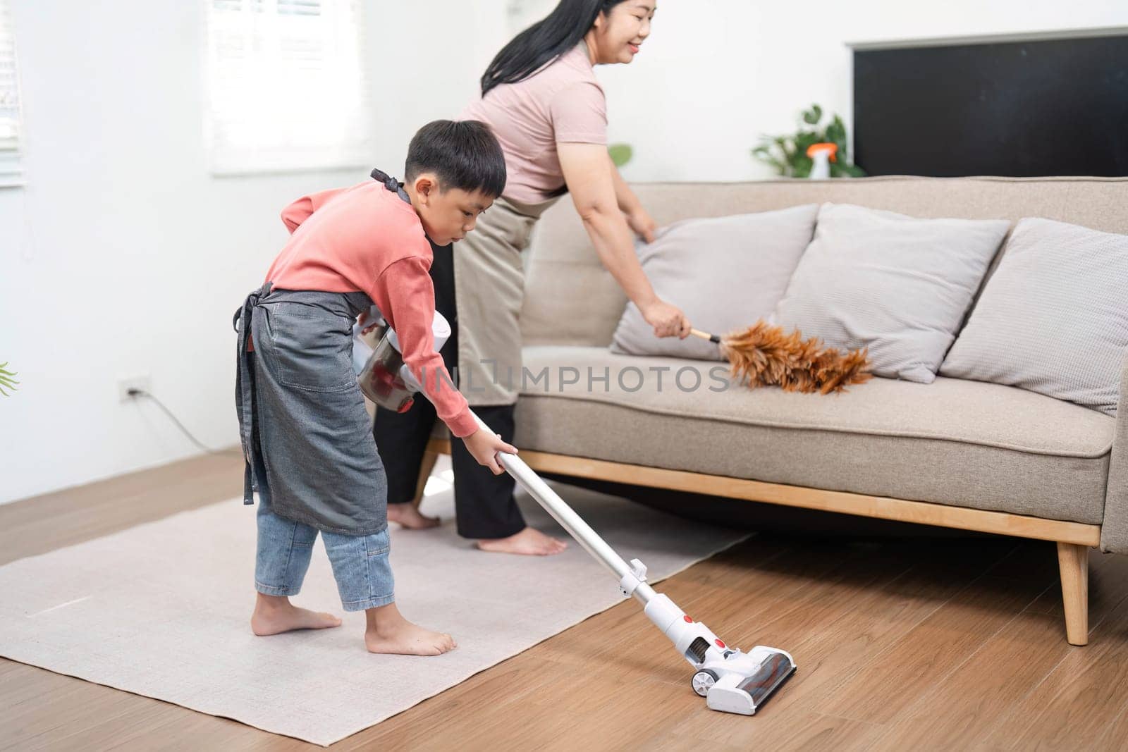 A mother and her son are actively engaged in cleaning their home, showcasing the joy of shared chores and family dynamics in a nurturing environment.