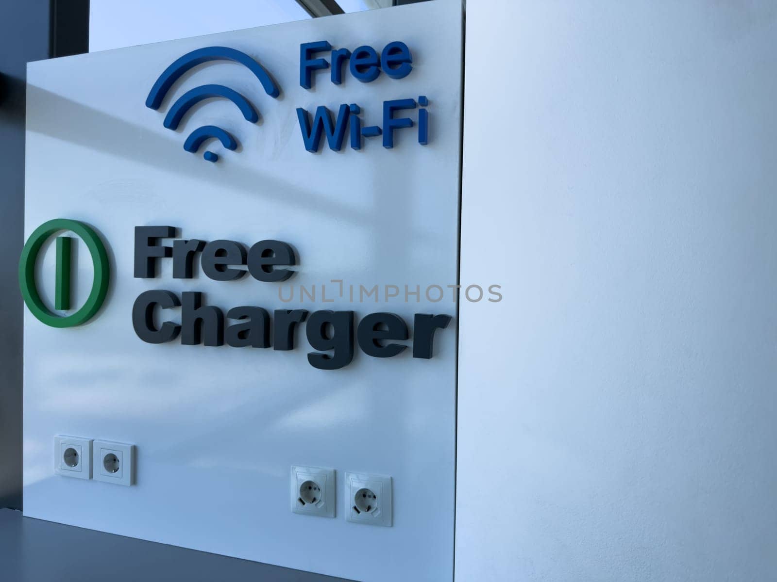 Modern indoor sign offering free Wi Fi and charging outlets, symbolizing traveler friendly digital infrastructure and essential services in public spaces like airports or stations