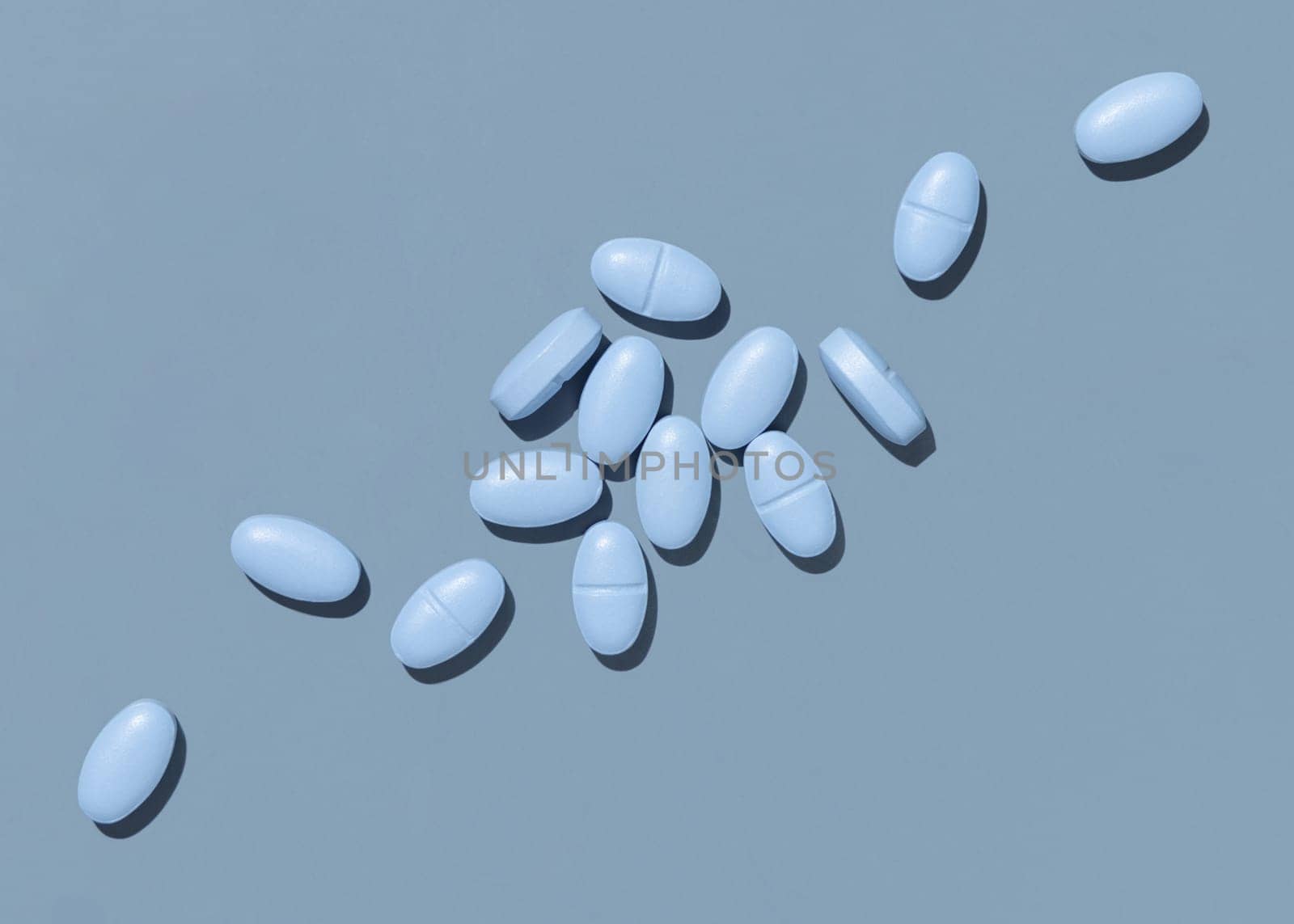 Blue medical pills on blue top view, hard light. Medicinal treatment for desease, pharmaceutical products for healthcare. Taking dietary supplements and vitamins