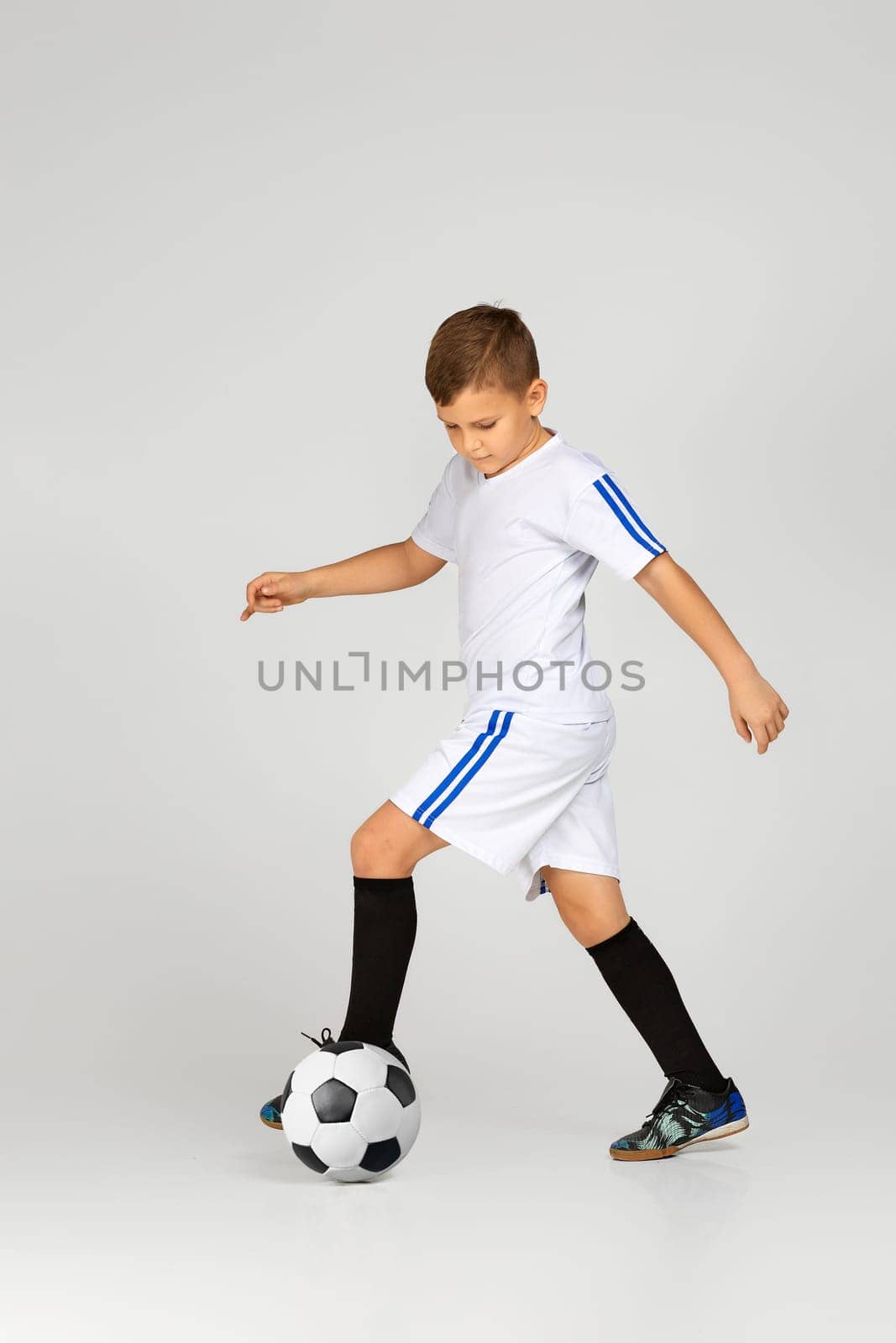 little child boy playing with soccer ball over studio background.