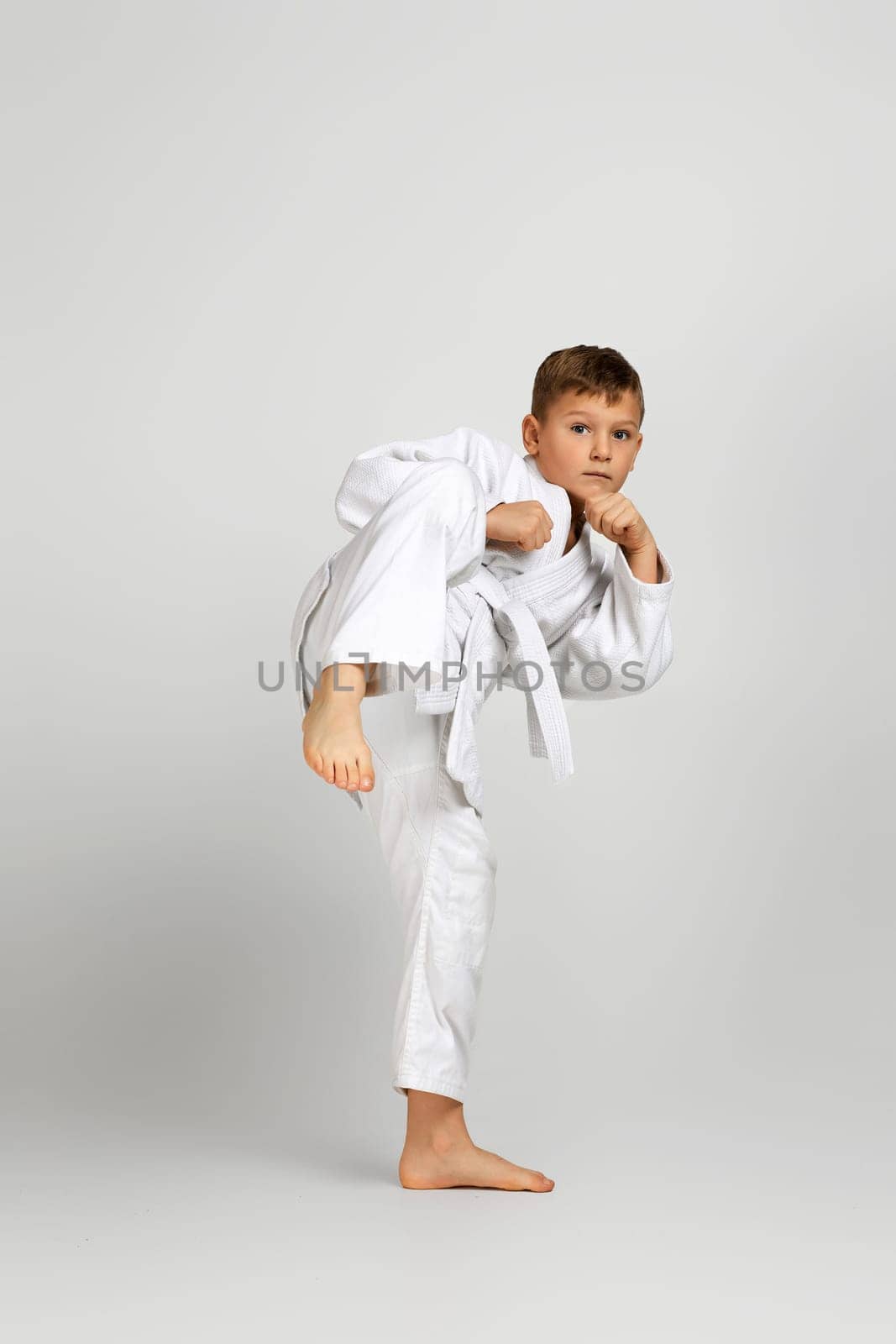 little child boy in a white karate kimono training. Full length portrait