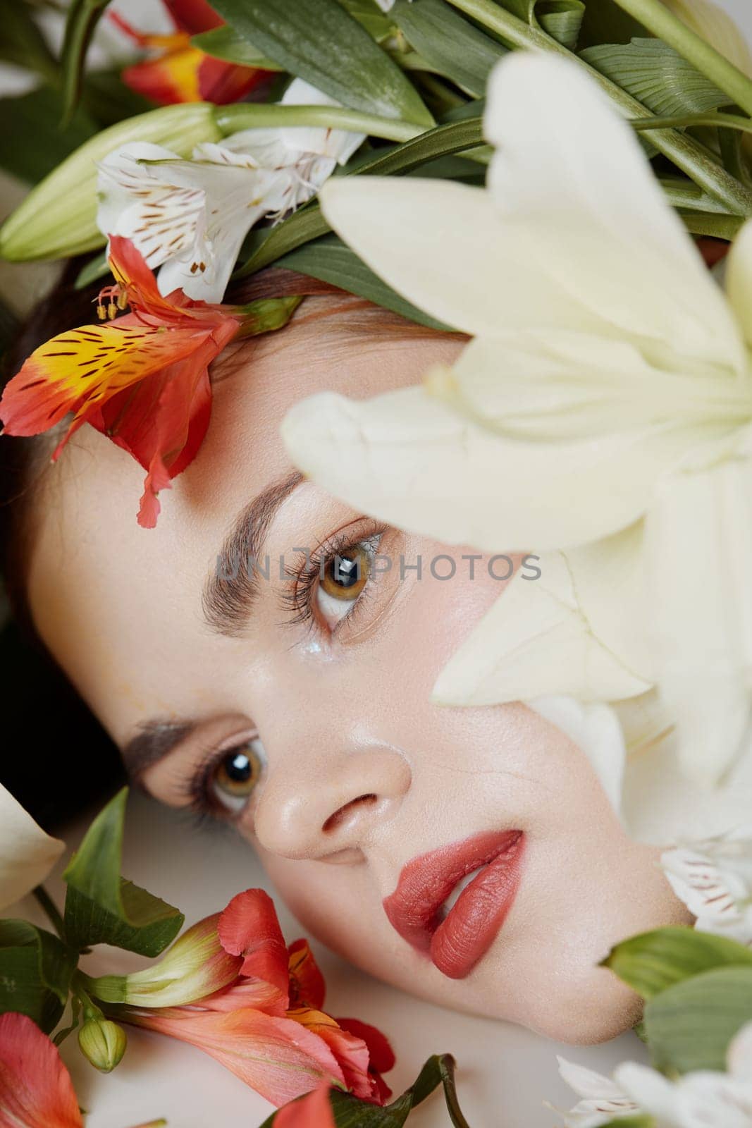 A serene young woman with natural makeup, surrounded by colorful flowers, evokes feelings of spring and renewal, perfect for promoting floral beauty concepts and skincare