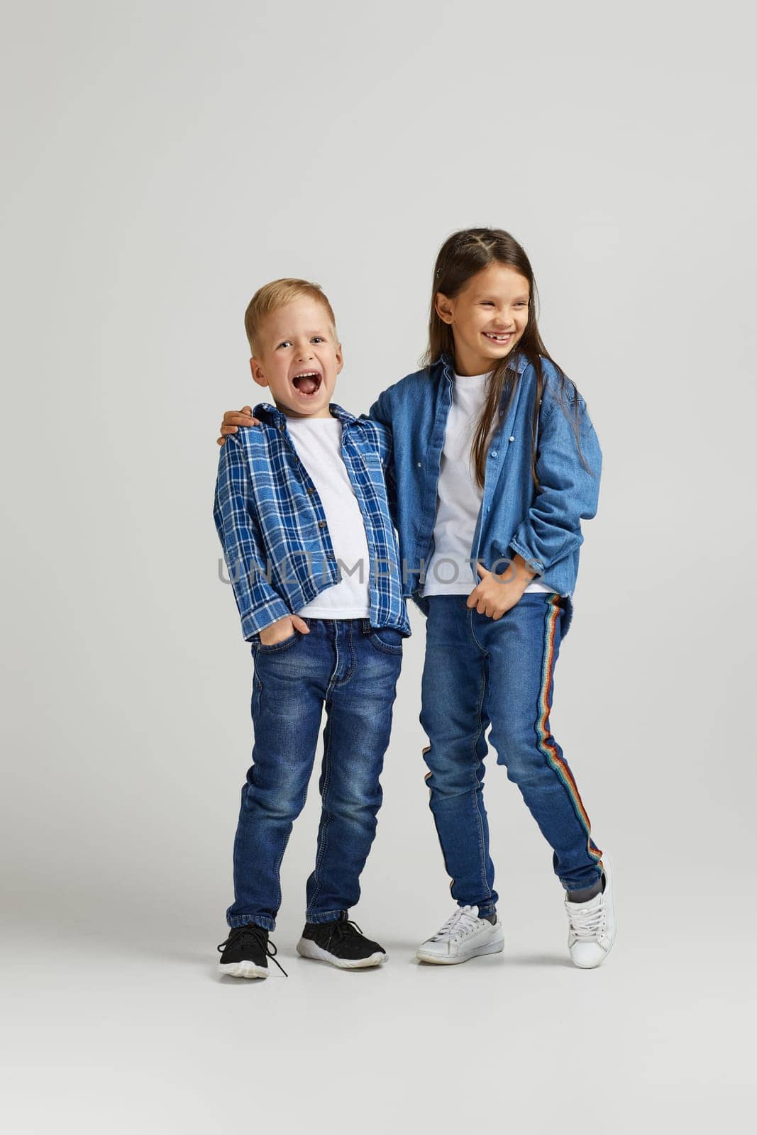 cute little boy and girl in stylish denim clothes. two happy children laughing and having fun