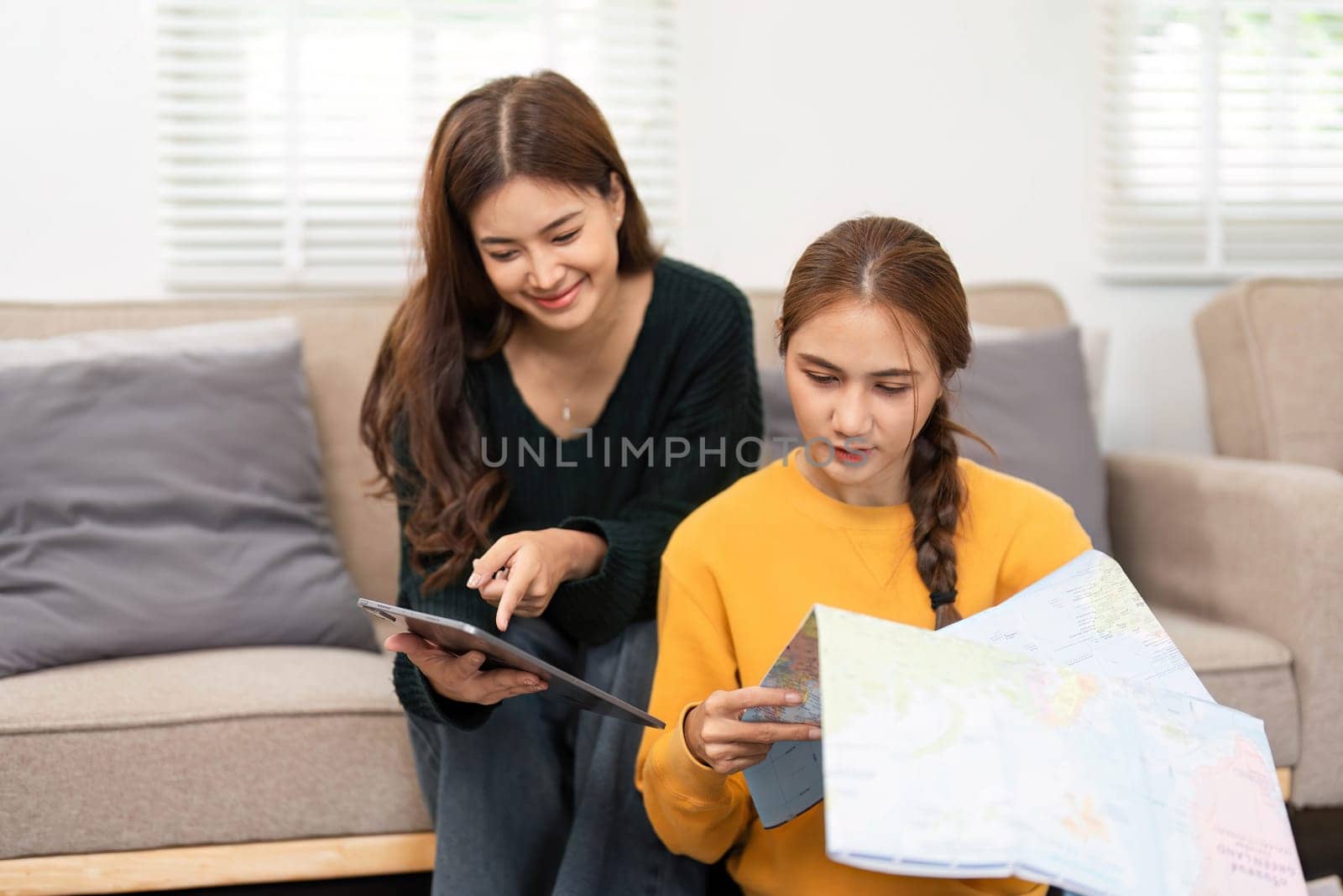 Two friends enjoying a moment of planning their travel, filled with laughter and focus as they pack a suitcase.